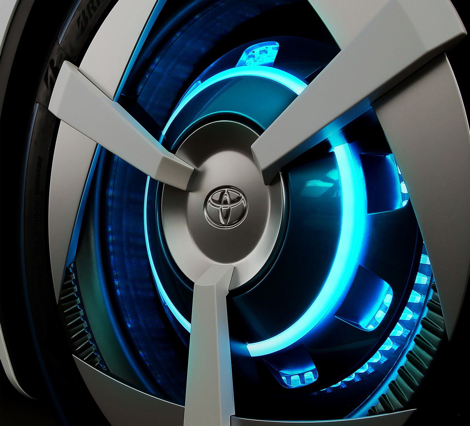 Close-up of a futuristic Toyota car wheel with glowing blue accents.