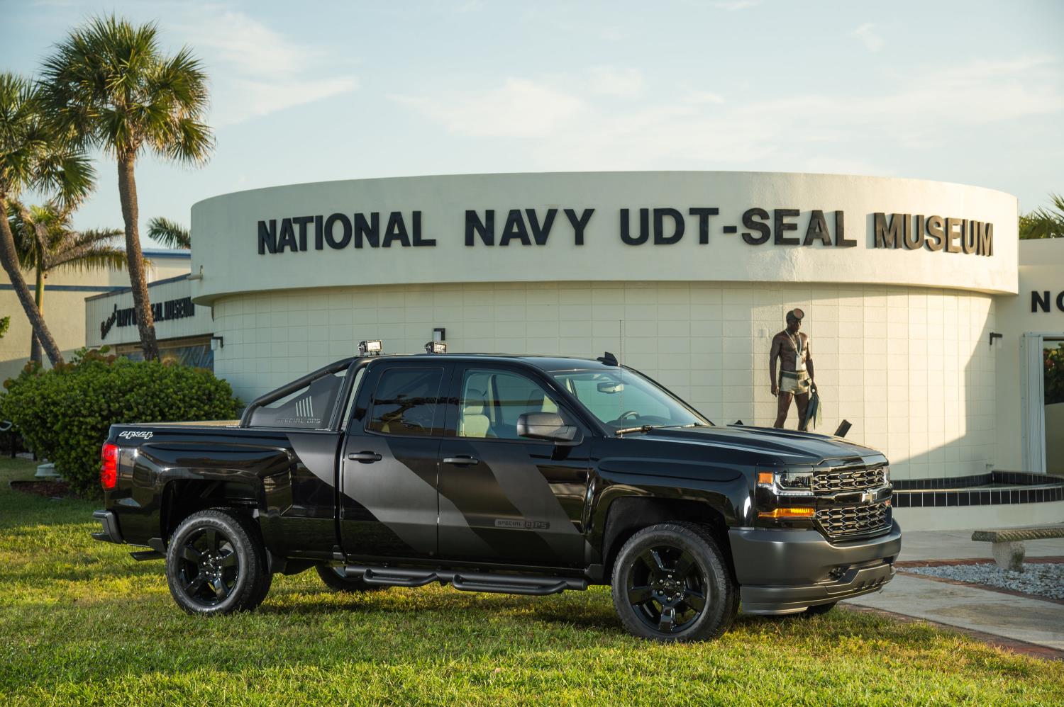 Black SUV parked outside National Navy UDT-SEAL base with personnel nearby.