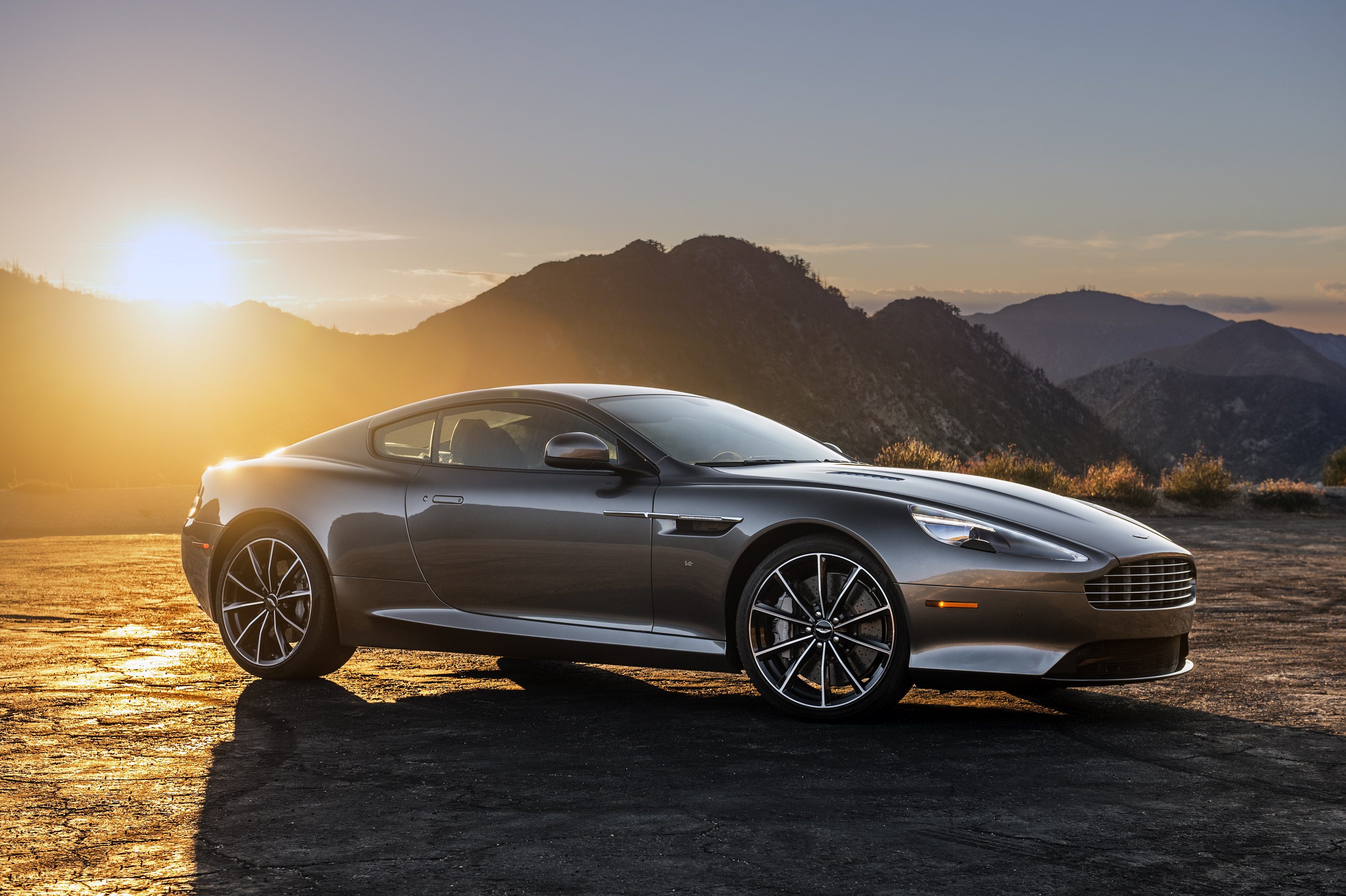 Sleek silver sports car parked with mountain sunset backdrop.
