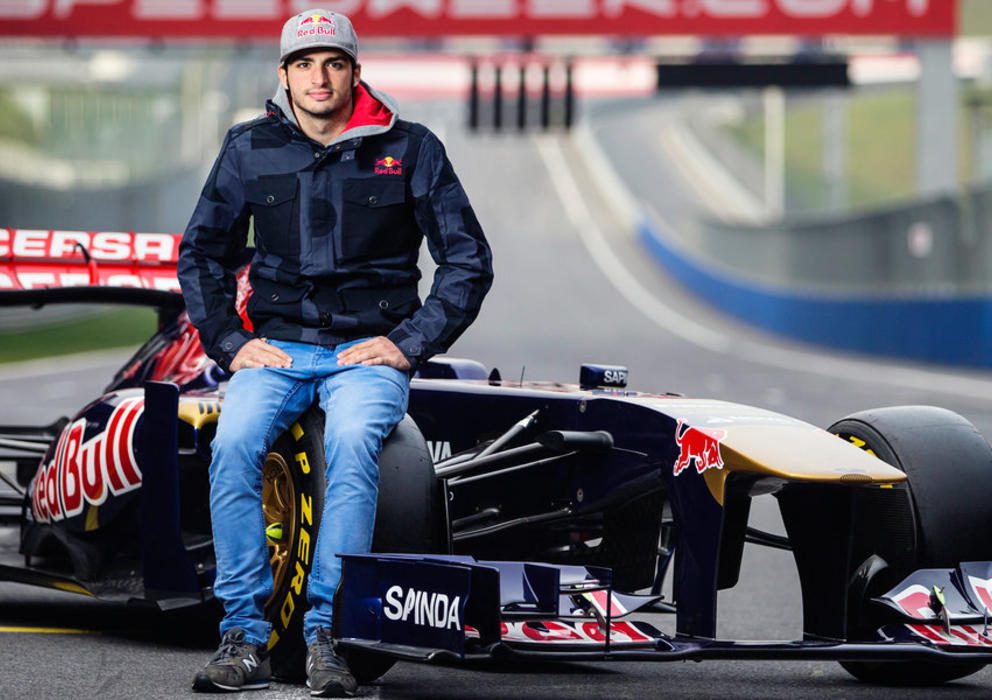 Man sitting on a Formula 1 car on a racetrack.