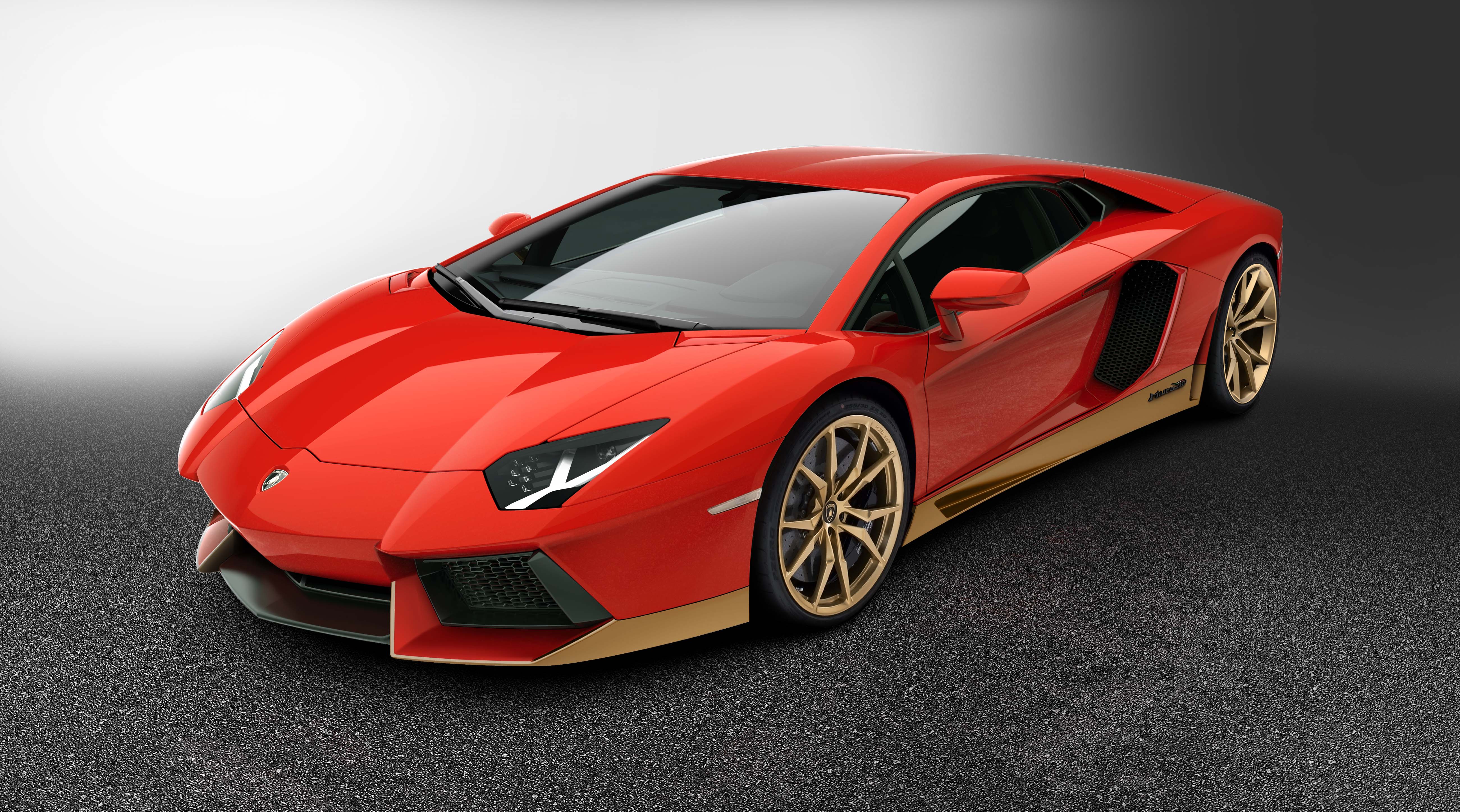 Sleek red sports car with gold rims parked on black asphalt.