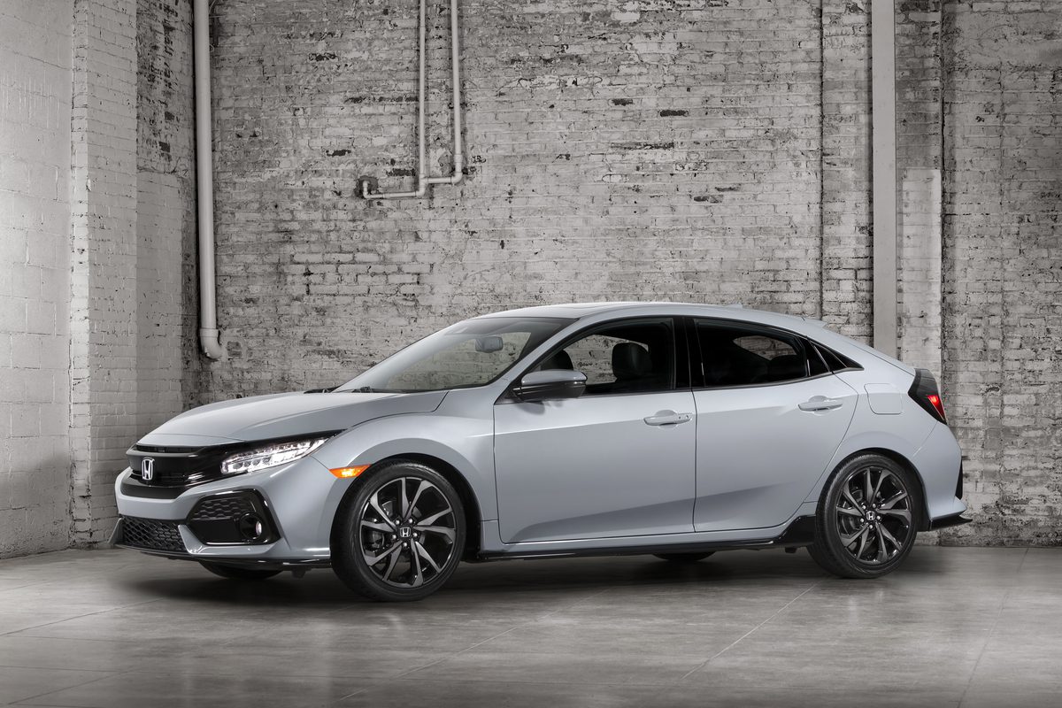 Sleek silver sedan parked indoors against a textured brick wall.