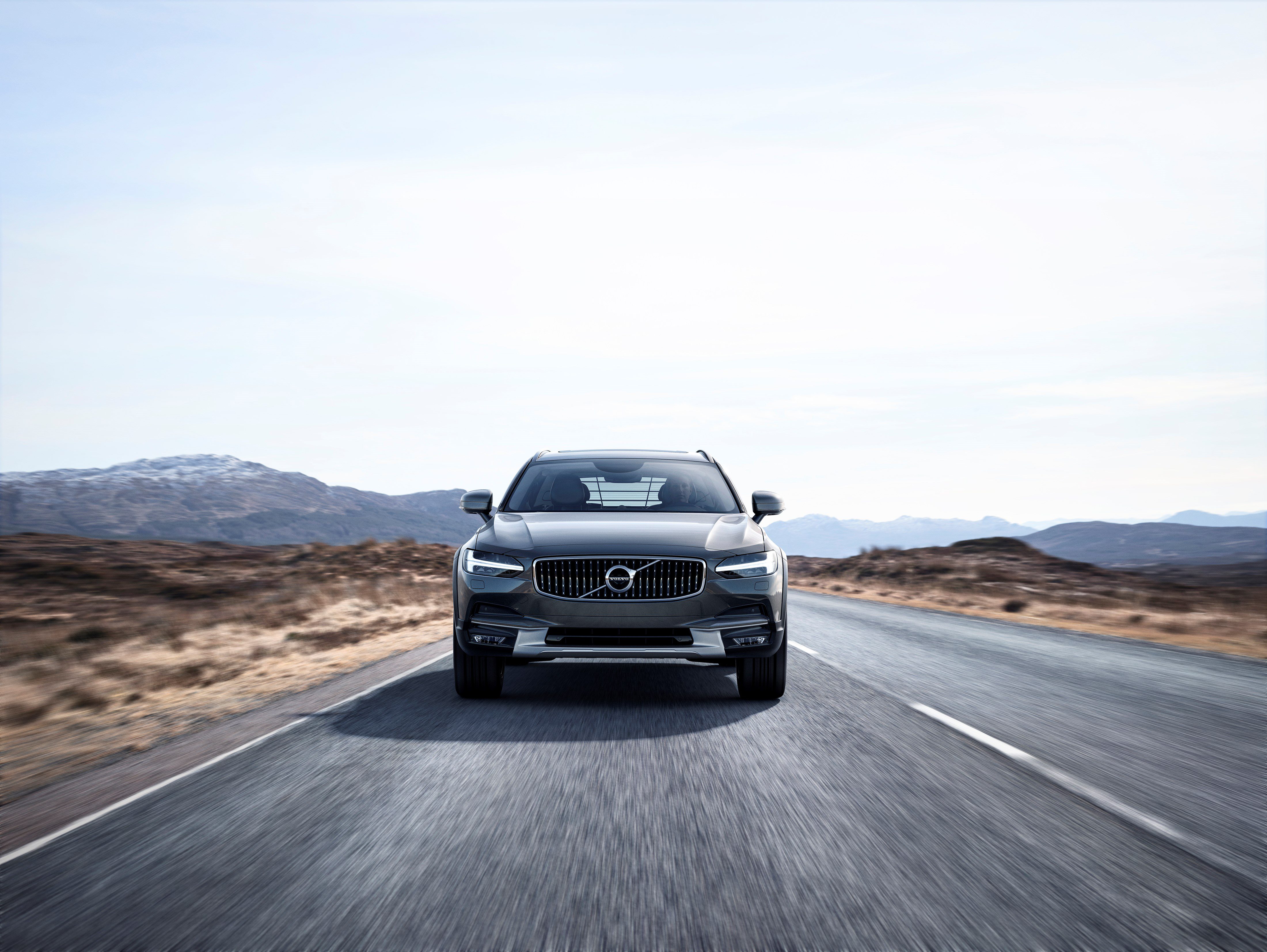 A black SUV driving on an open road in a desert landscape.