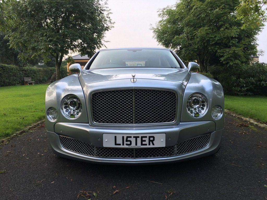 Front view of a silver Lister luxury car with a personalized license plate.