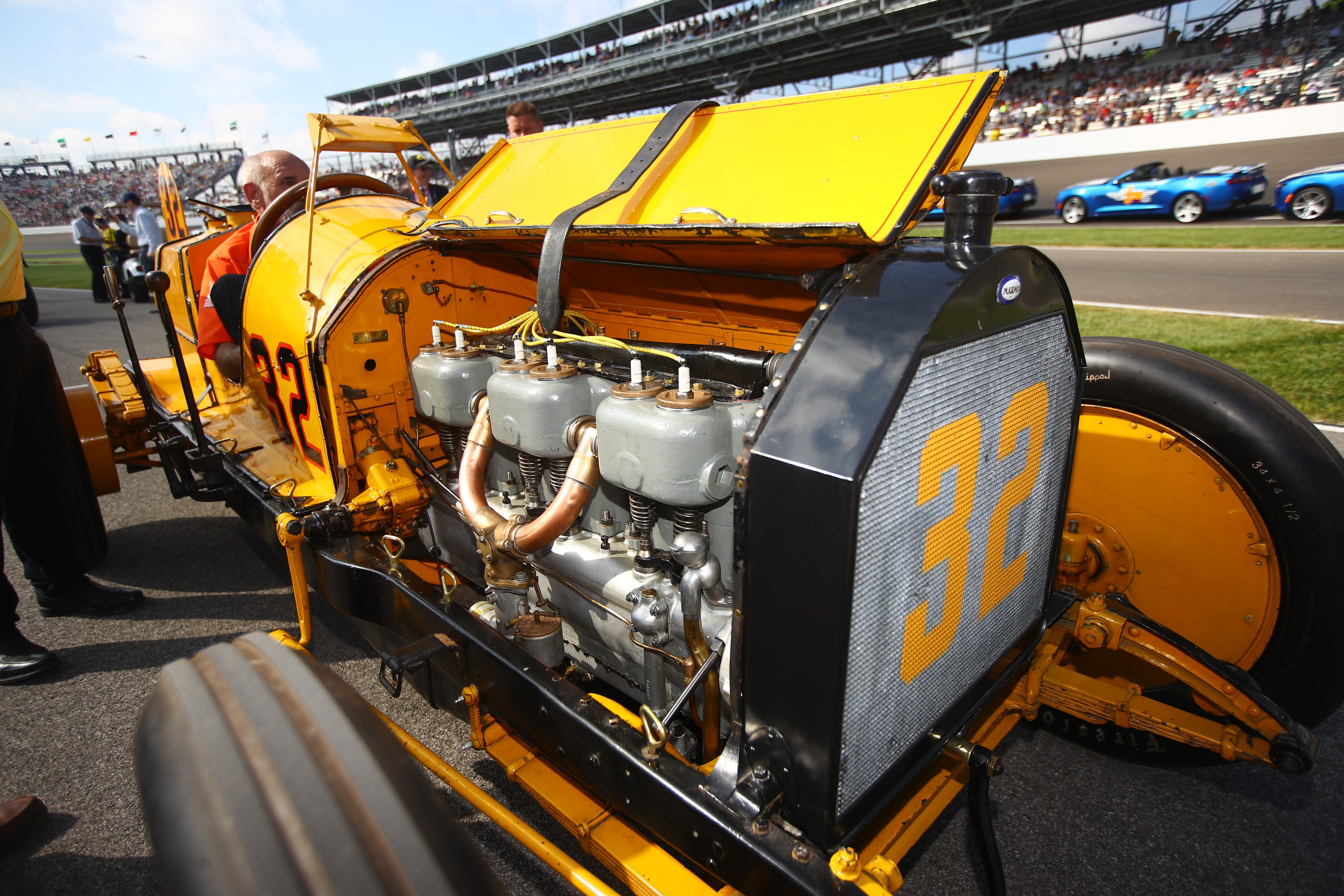 Vintage yellow race car with exposed engine and number 33 on display.