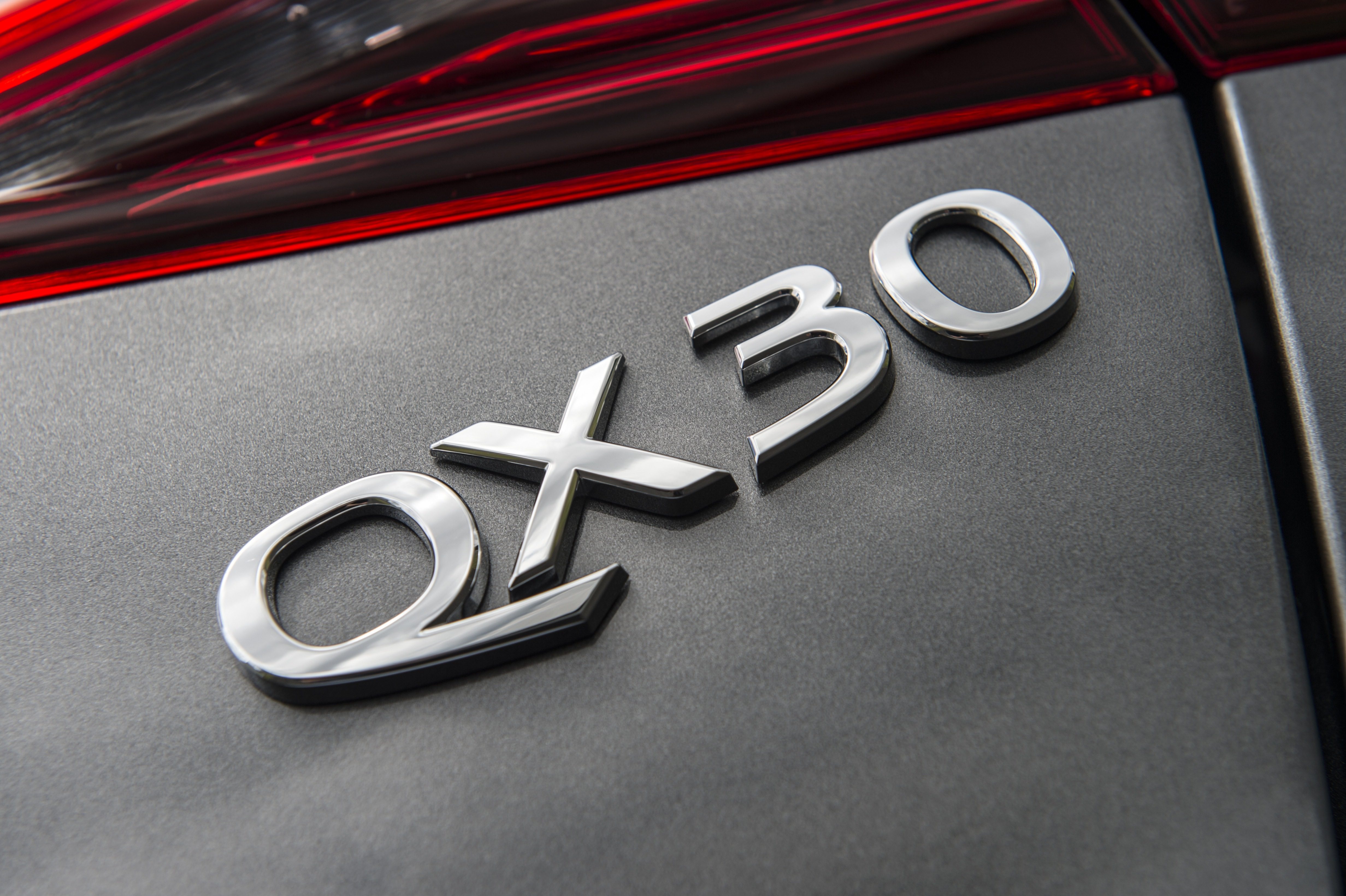 Close-up of Infiniti QX30 badge on a car.