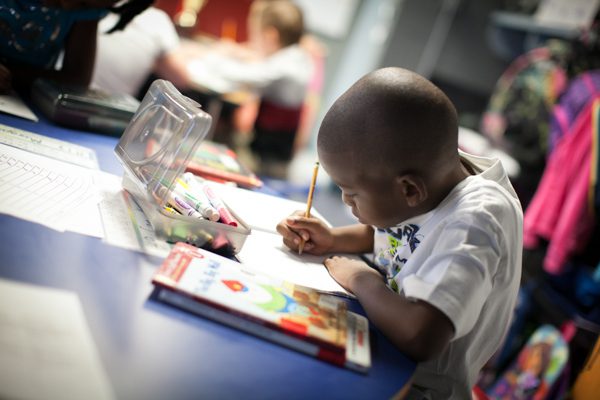 A child attentively painting in an art class.