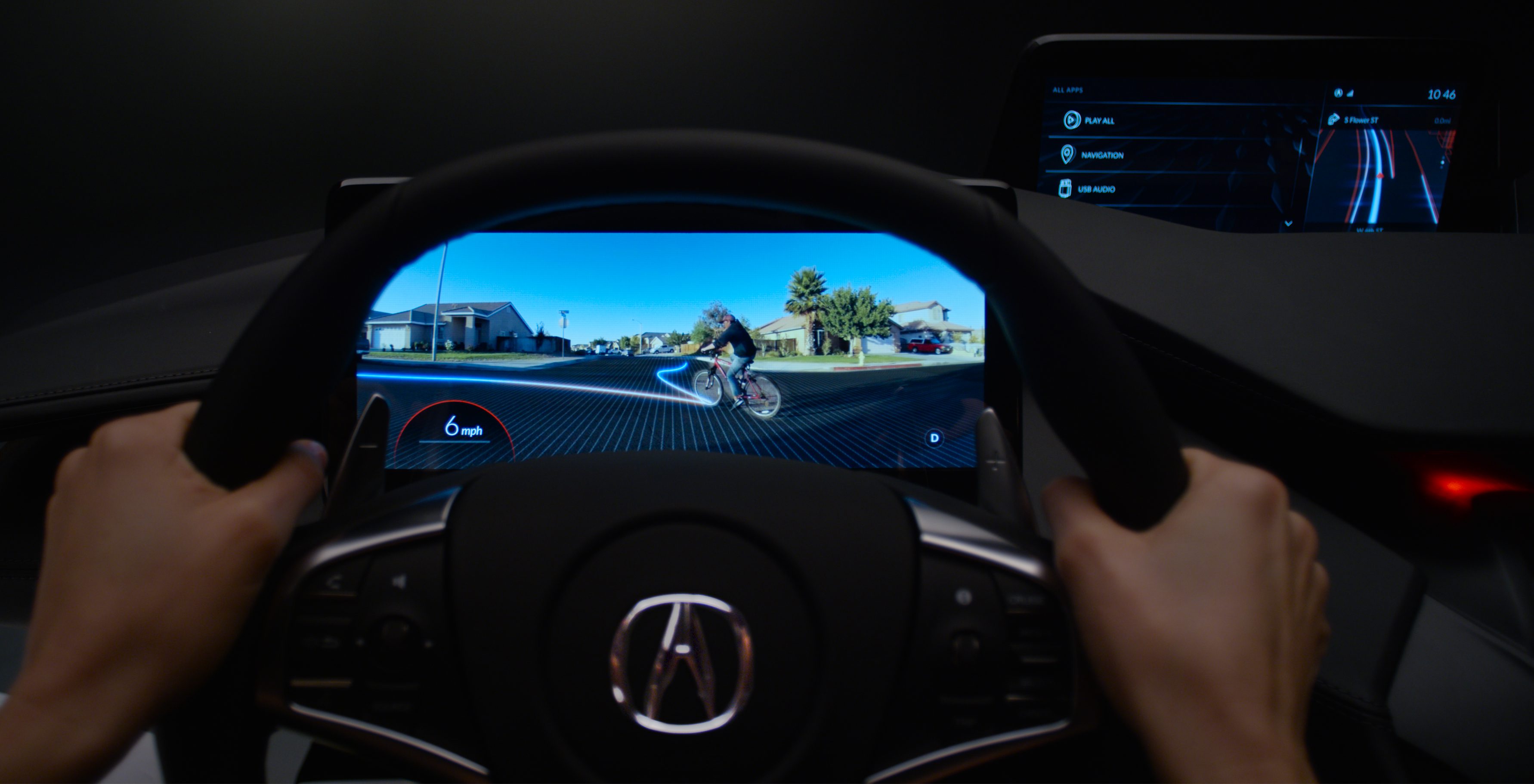 View from a car's steering wheel showing a cyclist on the road ahead.