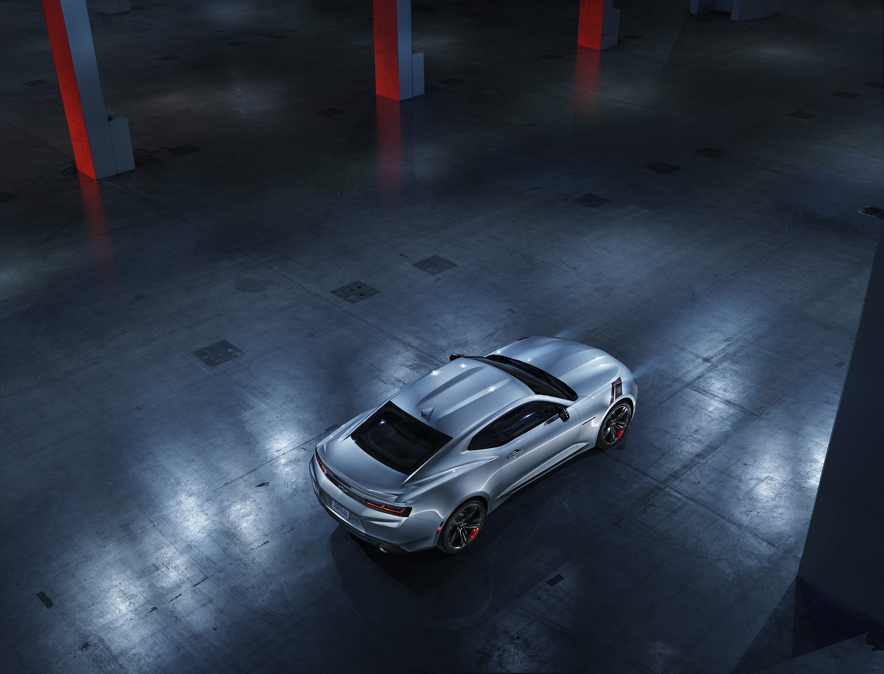 Silver sports car parked in a dimly lit urban garage at night.