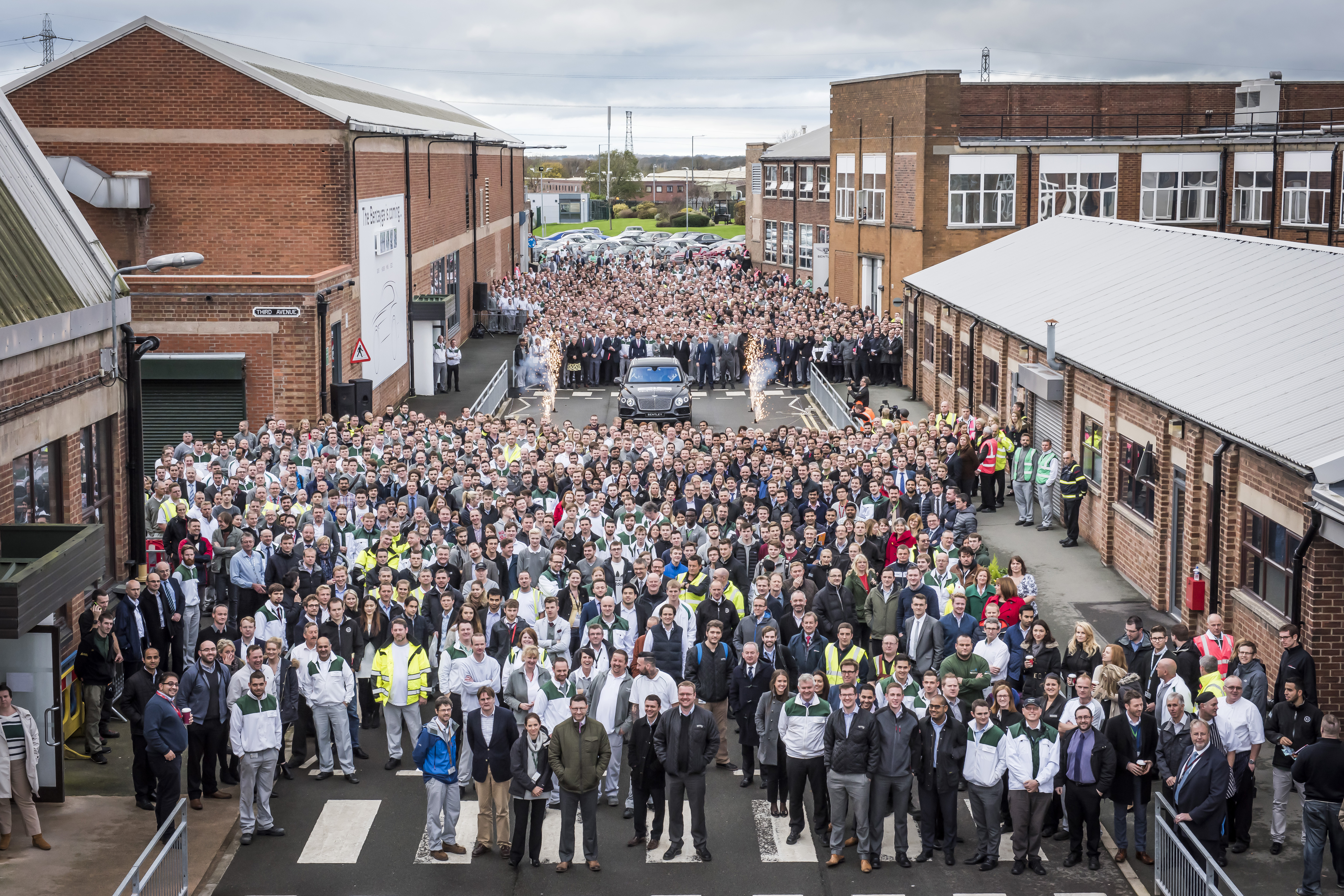 Massive crowd gathers in an industrial area for a large event or rally.