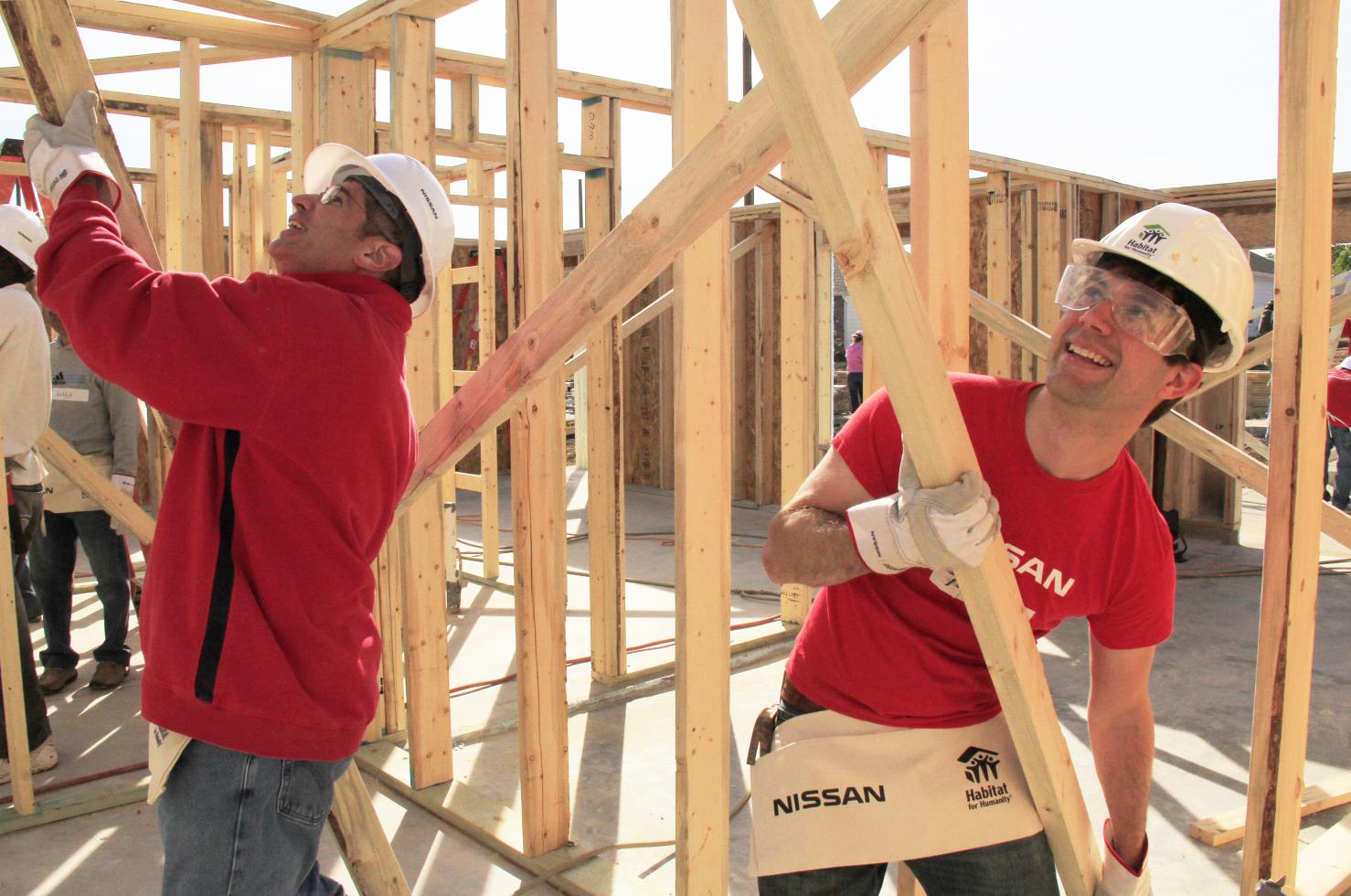 Two construction workers framing a wooden structure indoors.