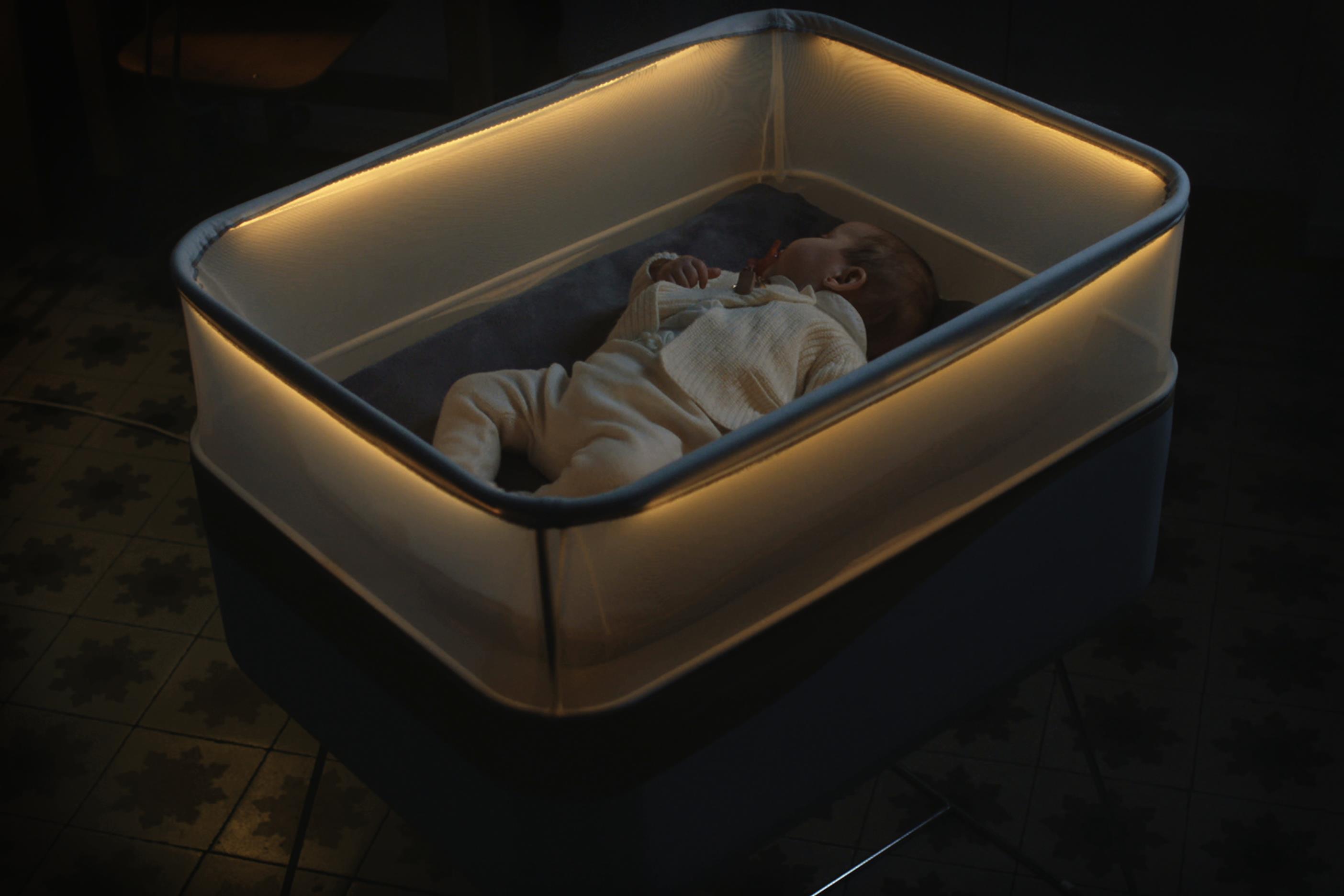 Baby peacefully sleeping in a softly lit inflatable crib at night.