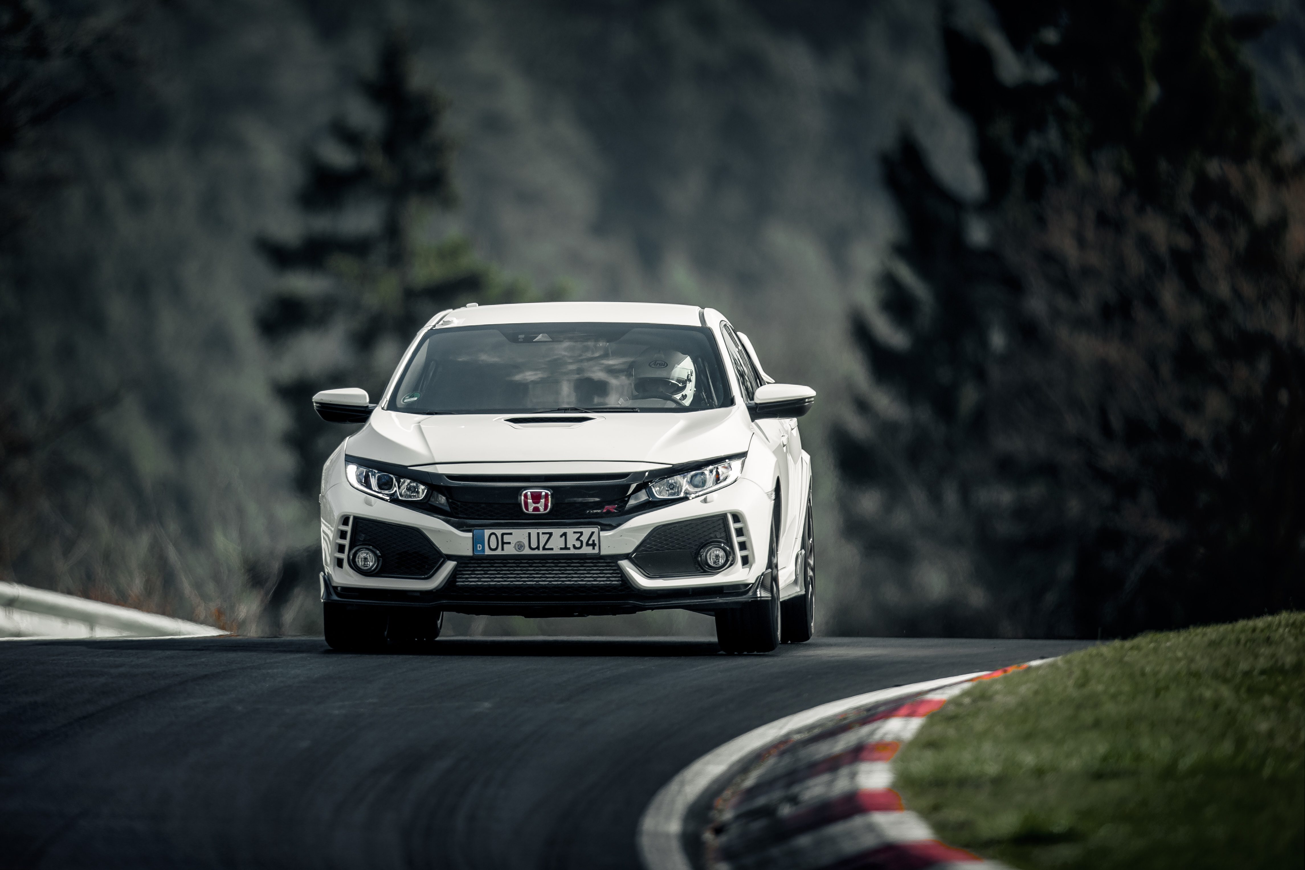 A white Honda Civic Type R racing on a track with blurred background.