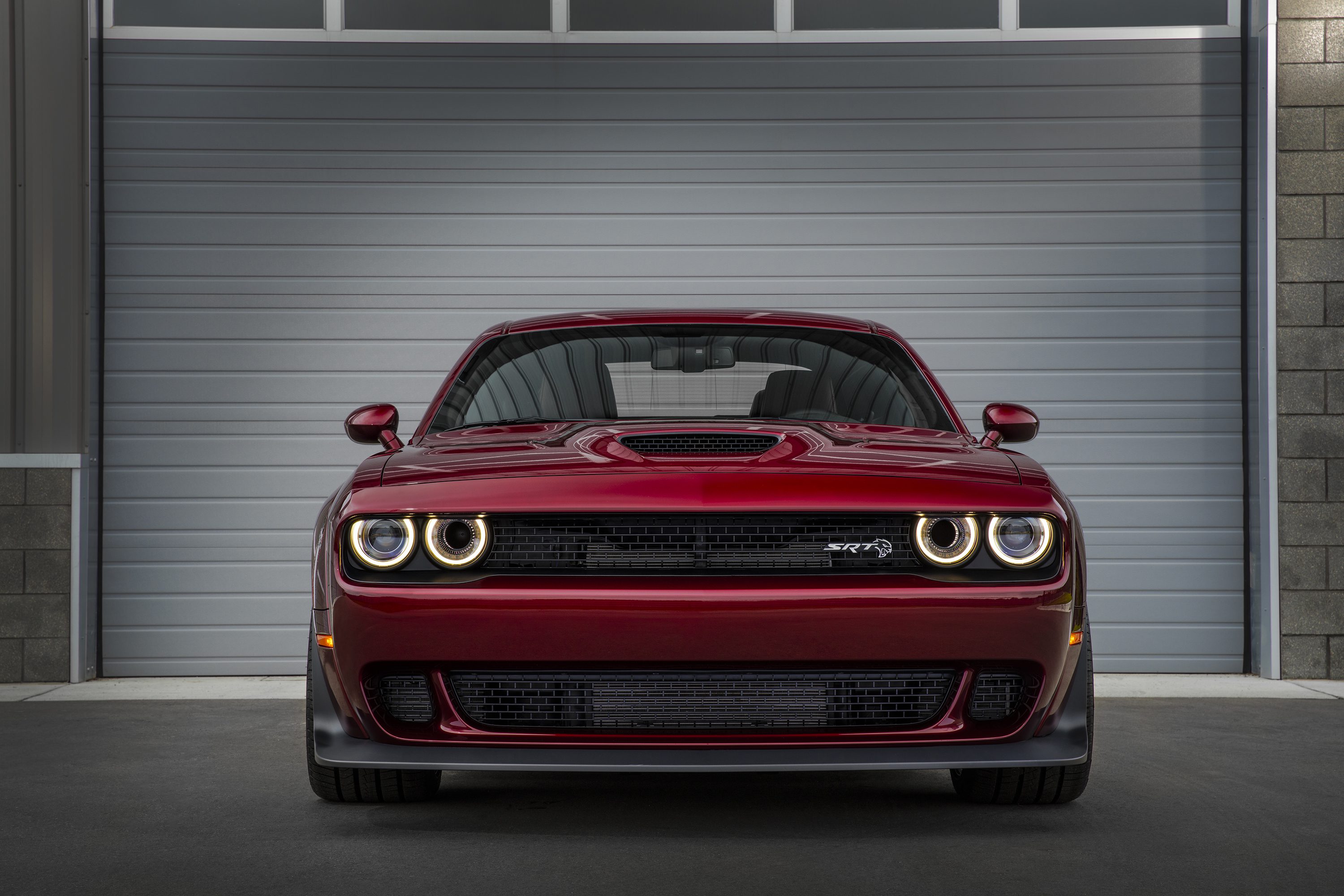 Front view of a red Dodge Challenger with glowing headlights.