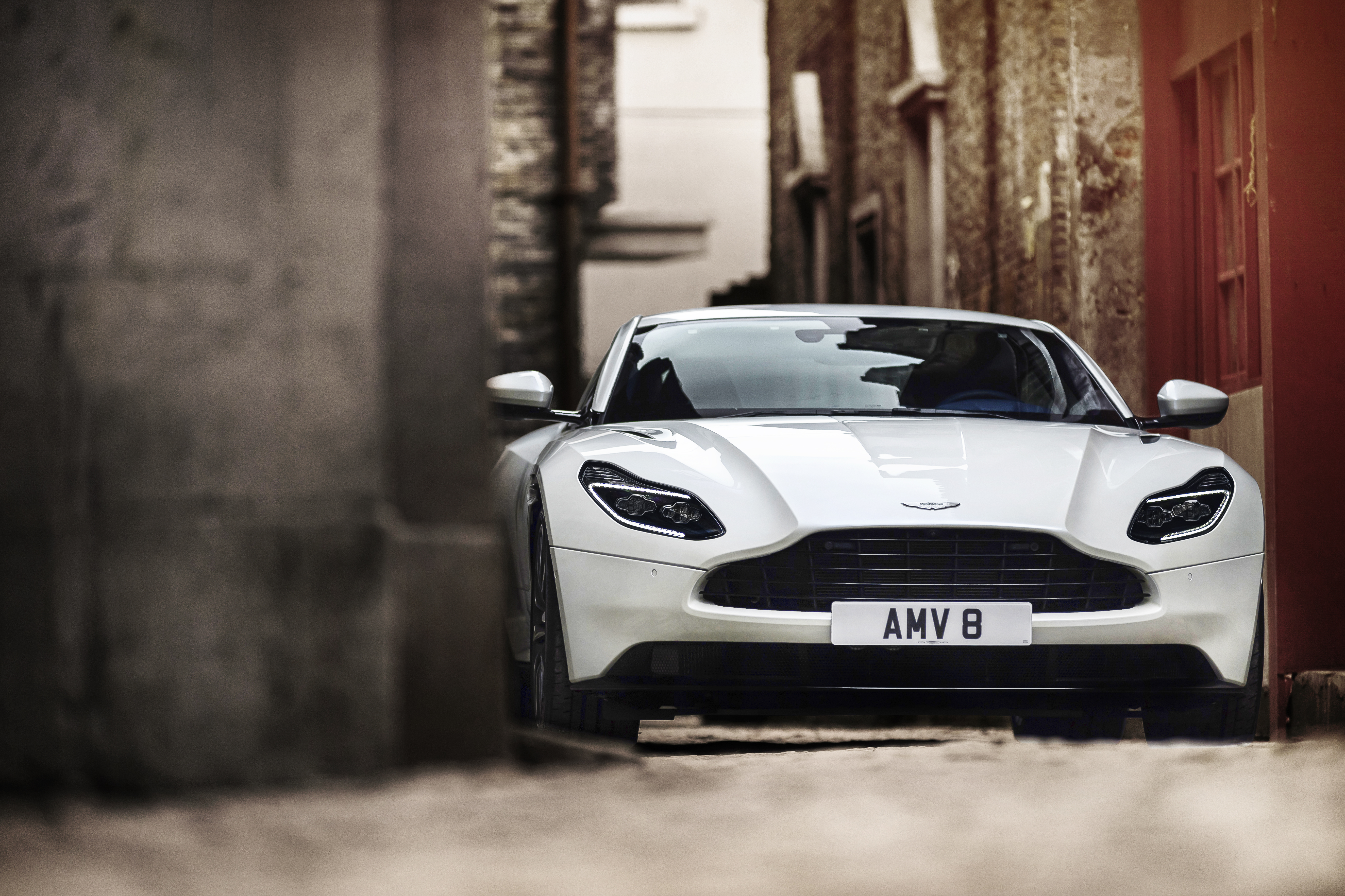 A sleek white sports car parked in a narrow alleyway.