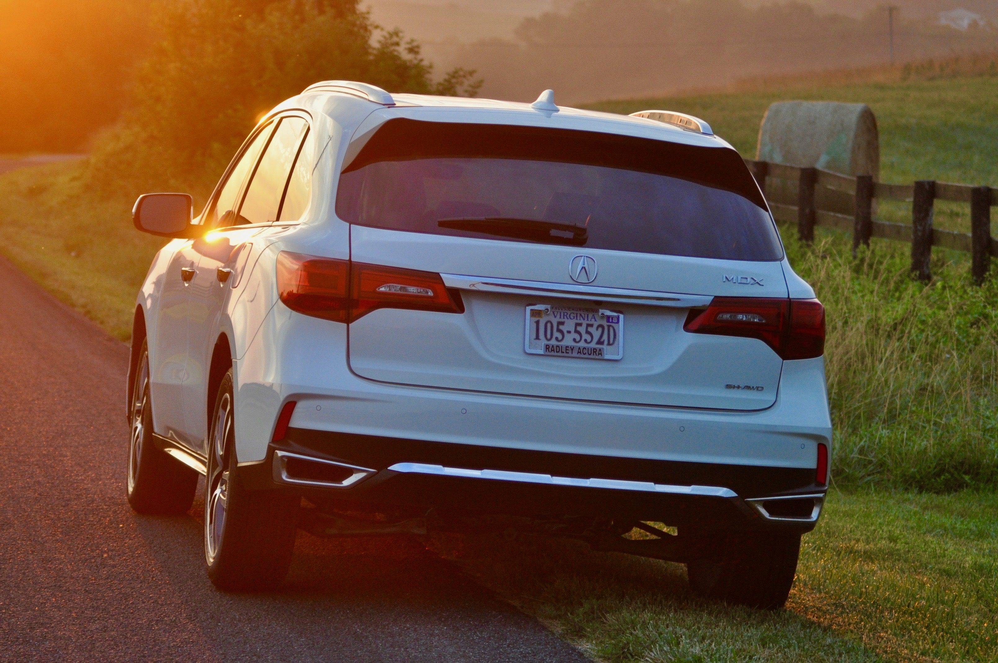 White SUV driving at sunset on a grassy road.