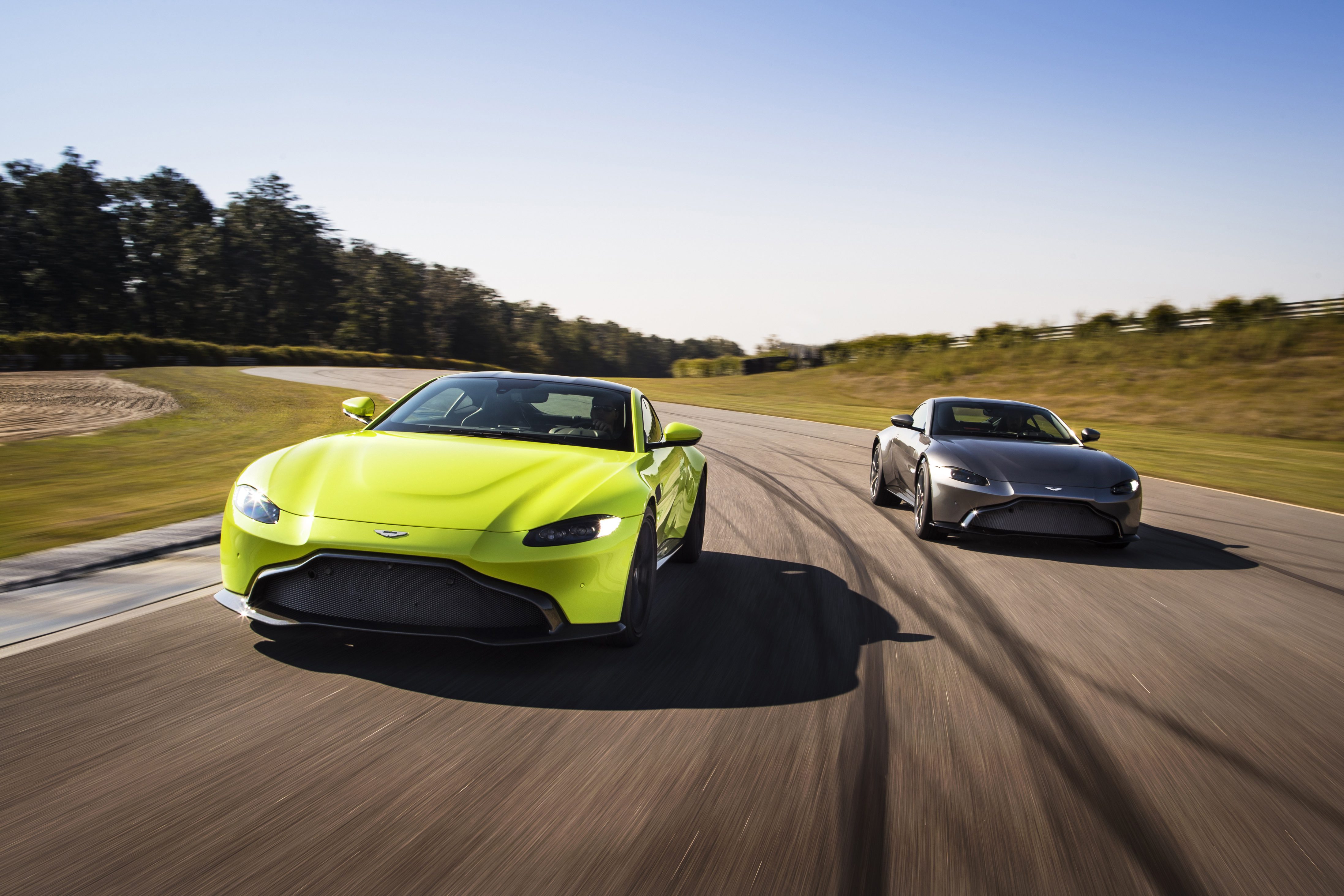 Two luxury sports cars racing on a sunny road.
