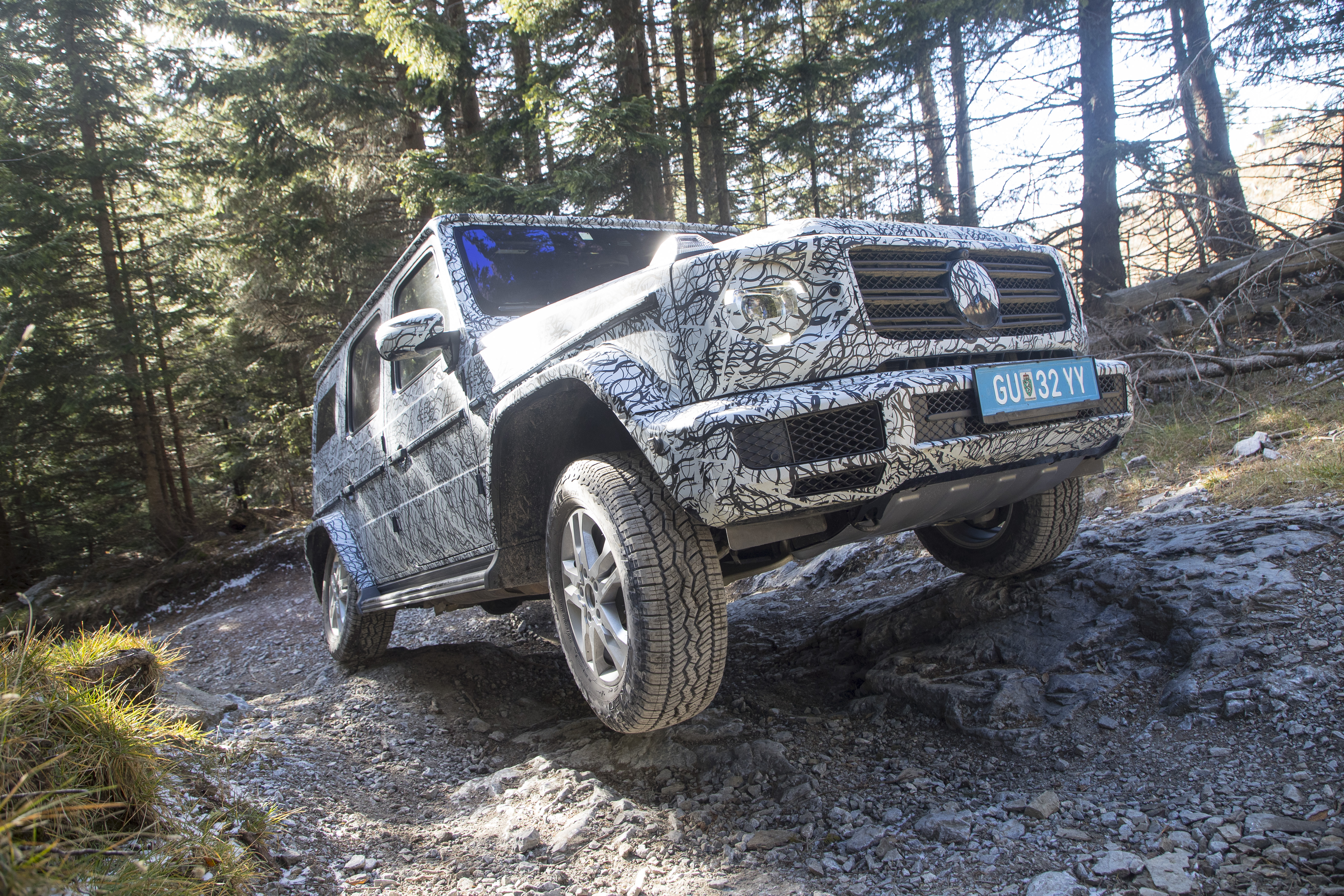 Mercedes-Benz G-Class navigating rocky terrain in a forest.