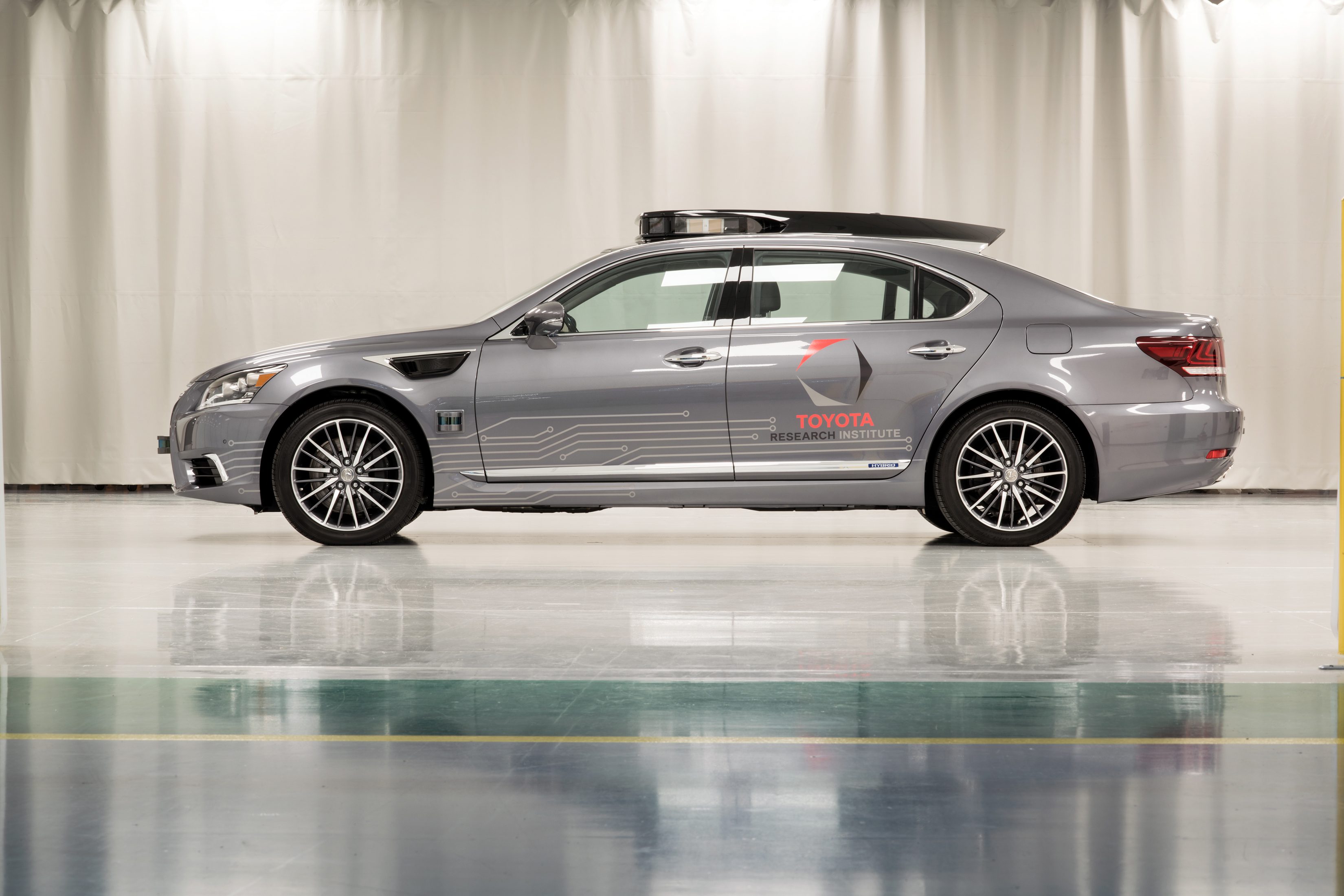 Side view of a sleek silver sedan with sporty wheels in a showroom.