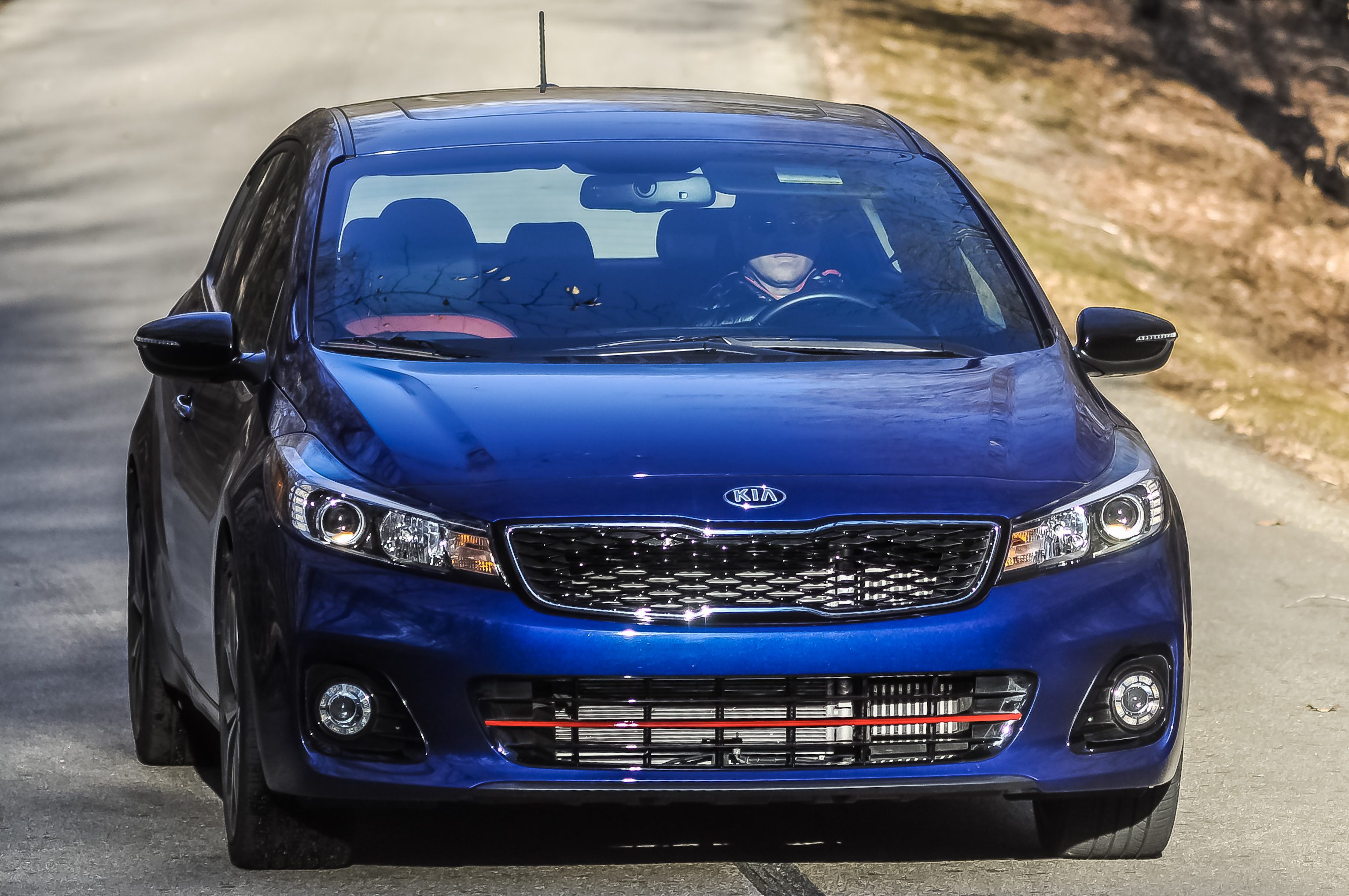 A blue Kia sedan parked outdoors on a sunny day.