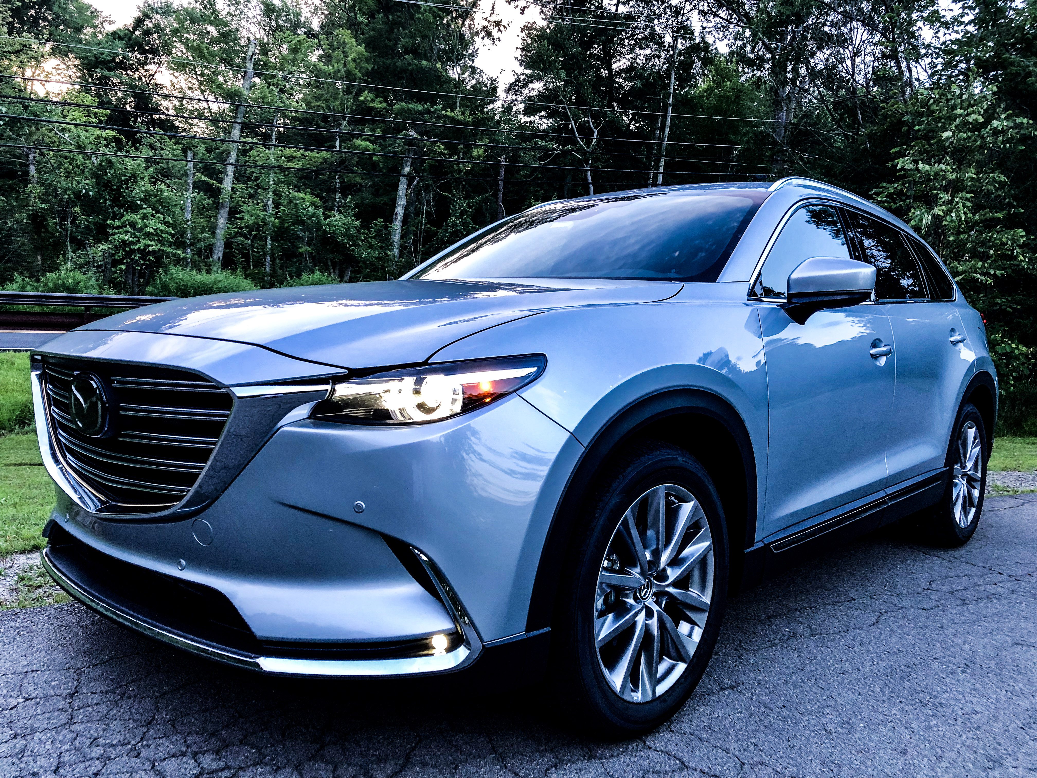 Sleek blue SUV parked on a quiet road surrounded by trees.