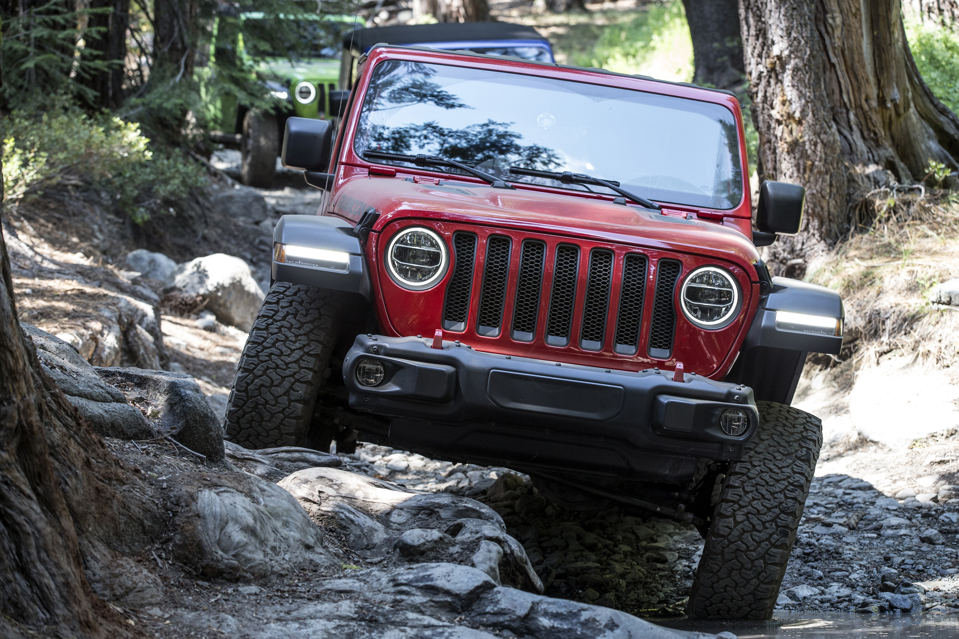 Red Jeep navigating rocky off-road terrain.