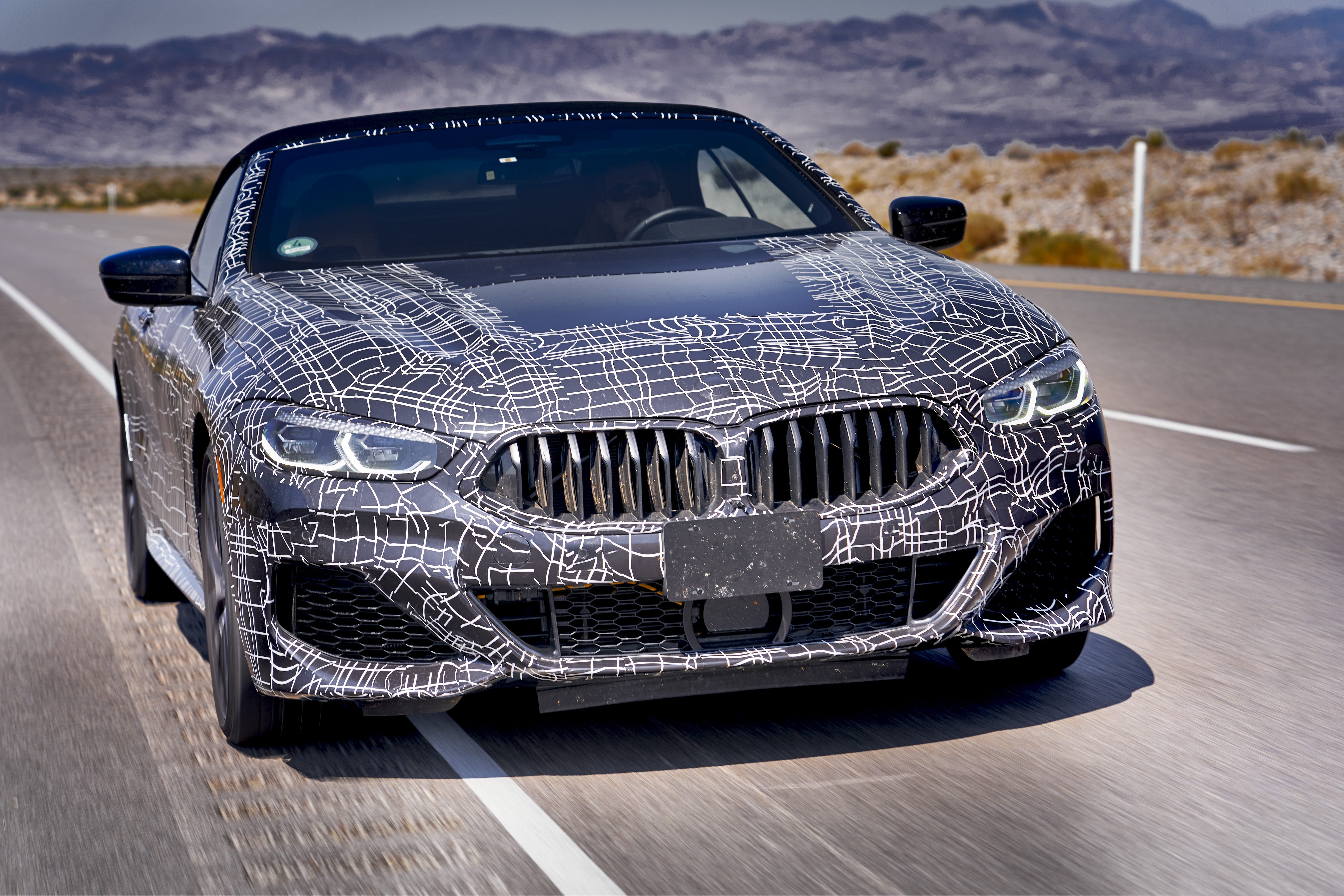 Camouflaged BMW car testing on road.
