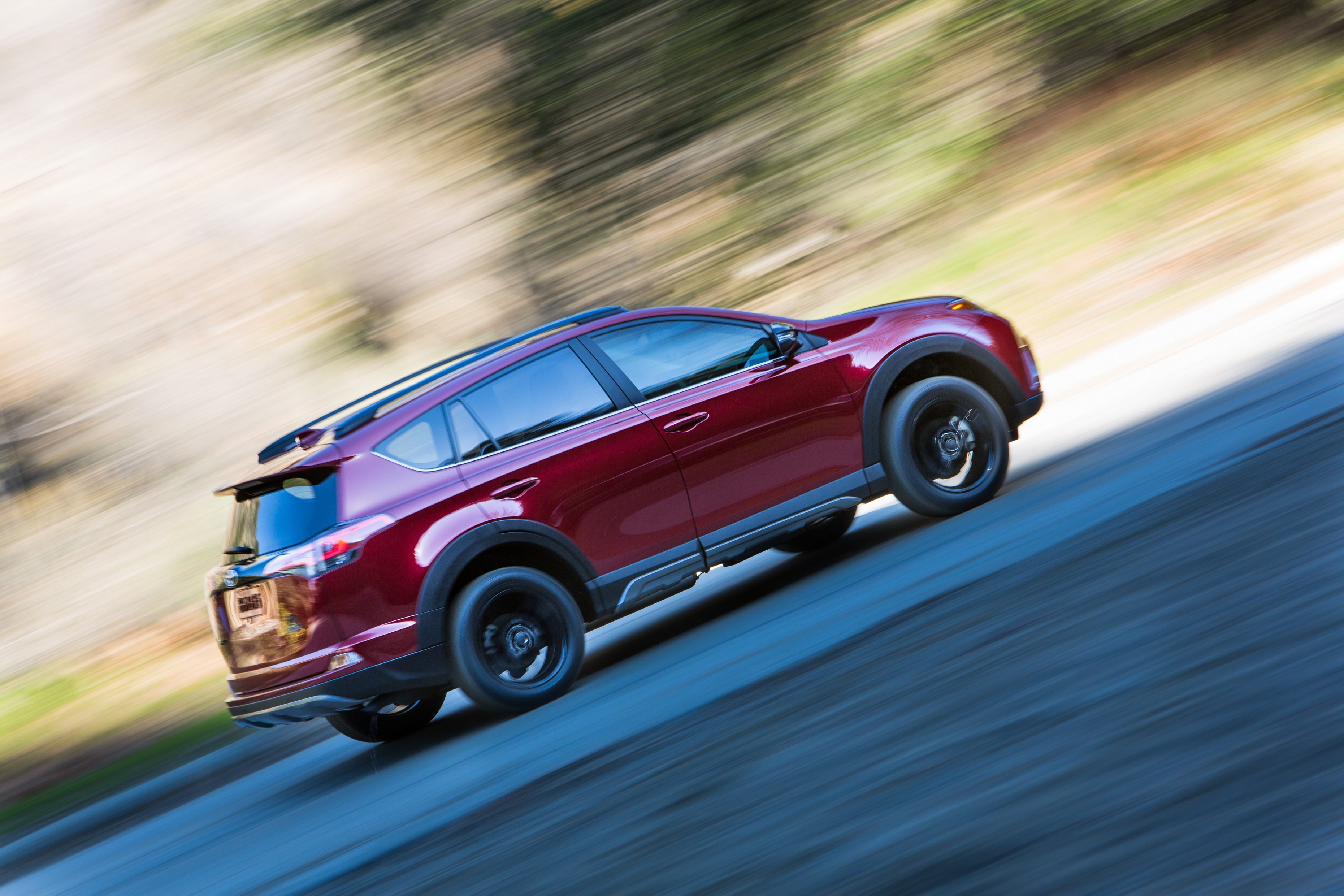 A red SUV driving fast on a curvy road.