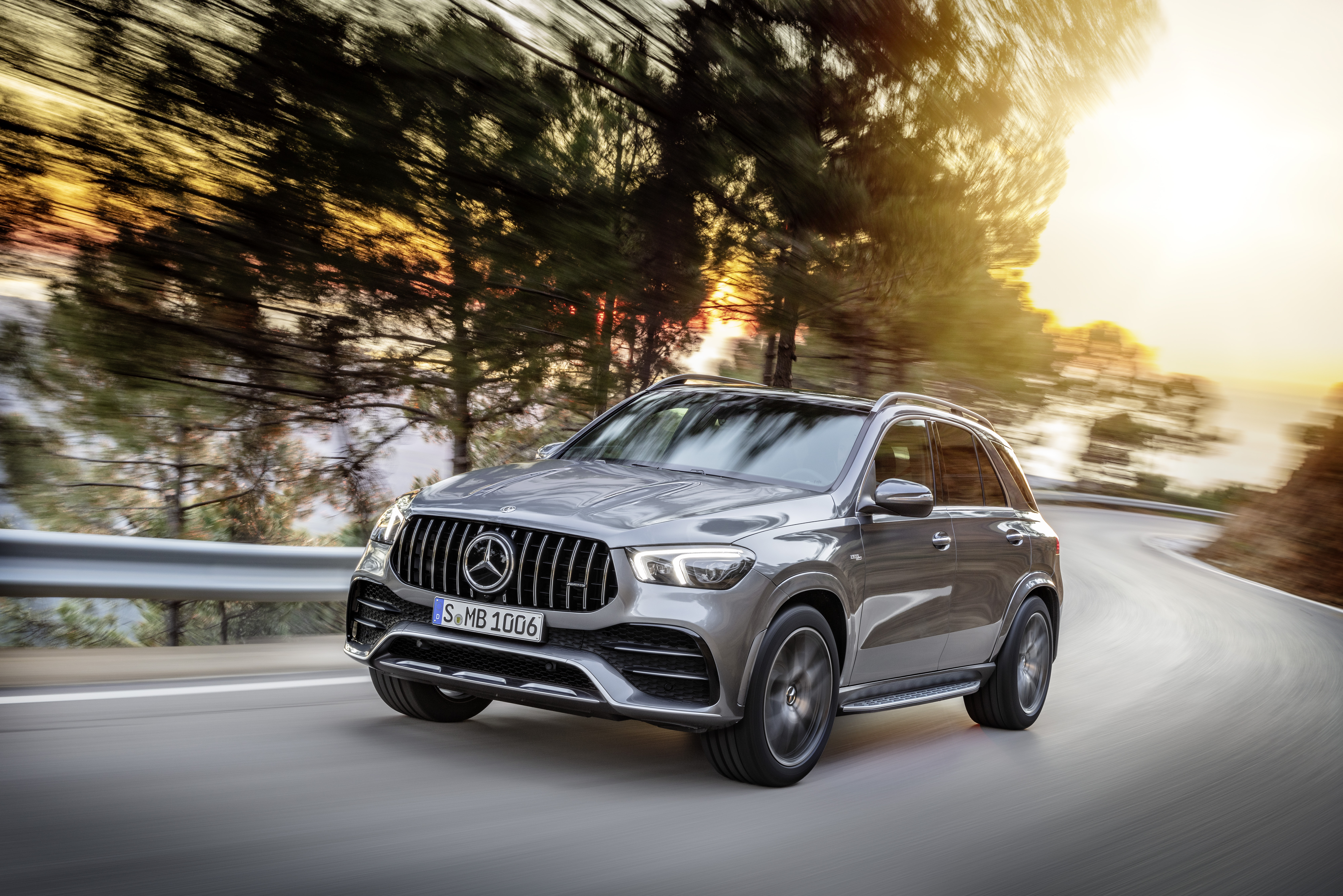 A sleek Mercedes-Benz SUV driving on a road at sunset.