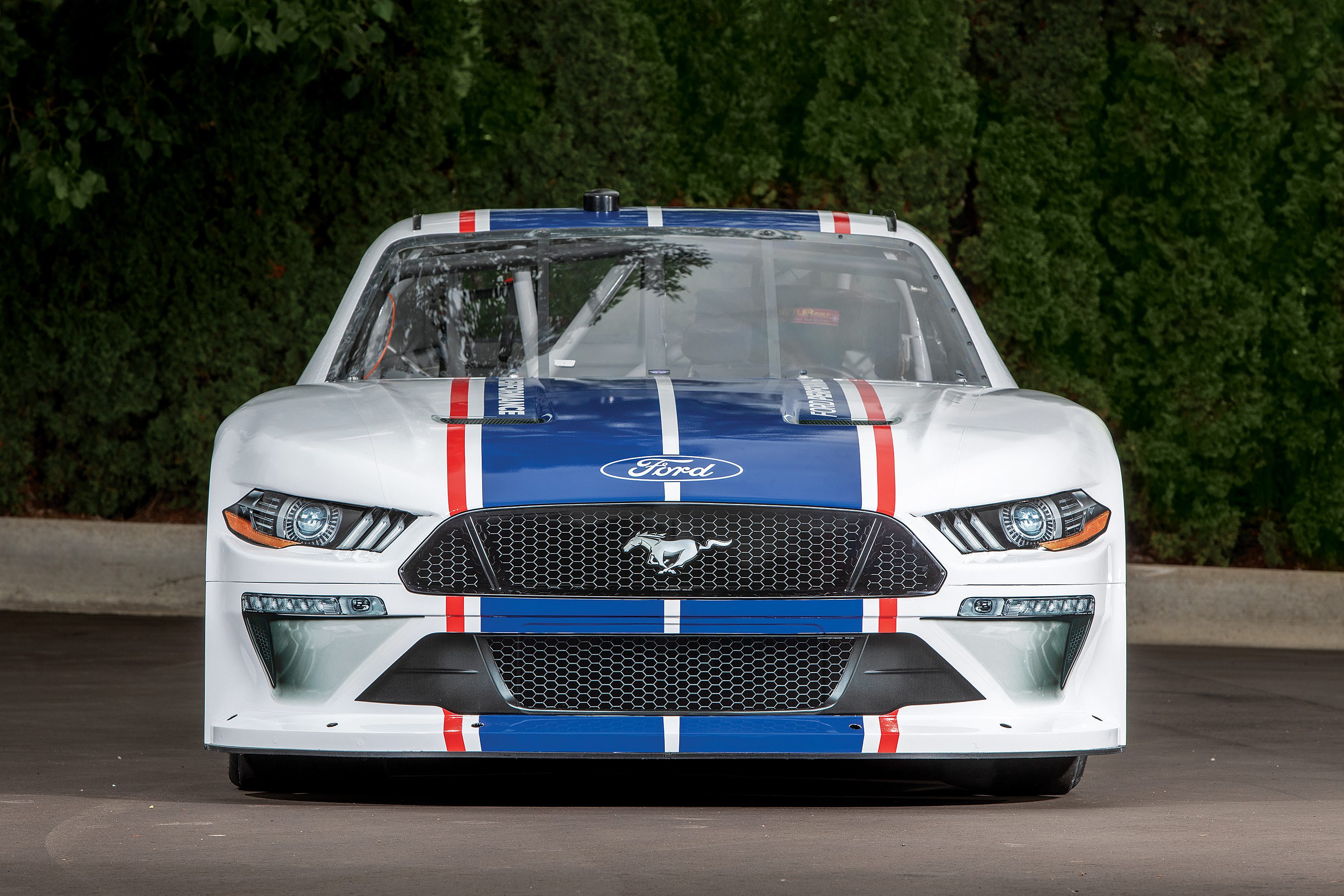 Front view of a white Mustang police car with red, white, and blue stripes.