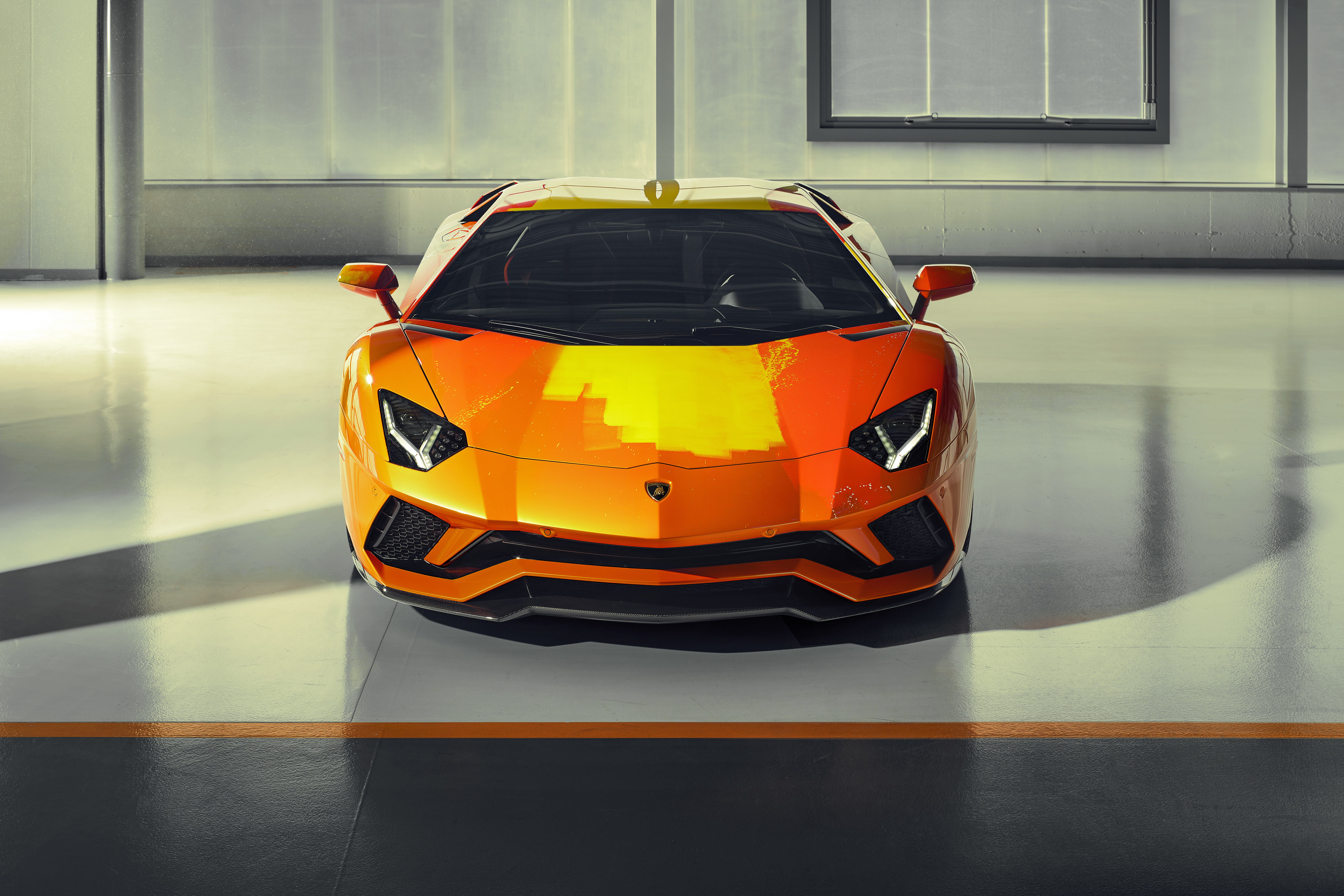 A sleek orange sports car parked indoors with dramatic lighting.