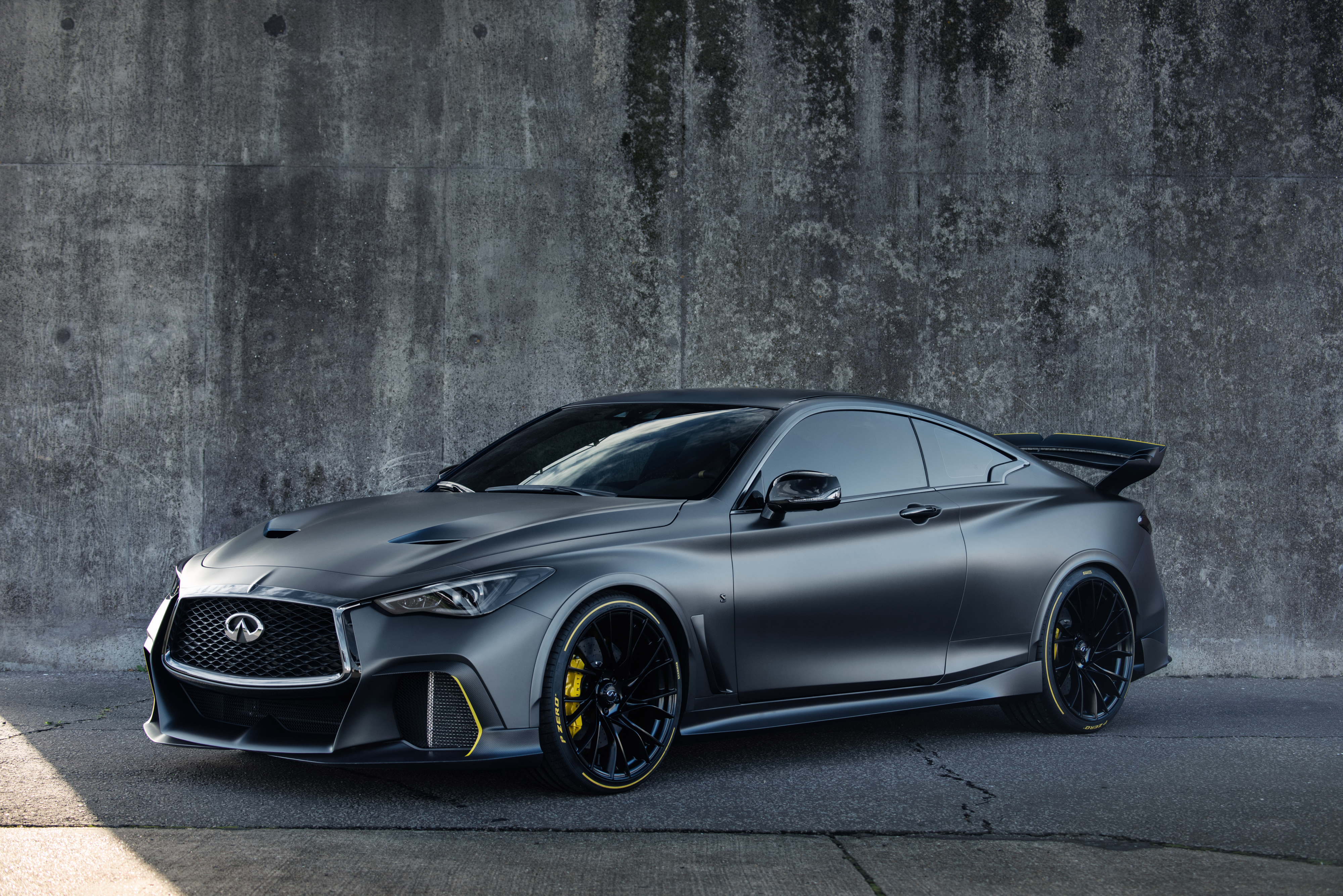 Sleek black sports car parked against a textured concrete wall.