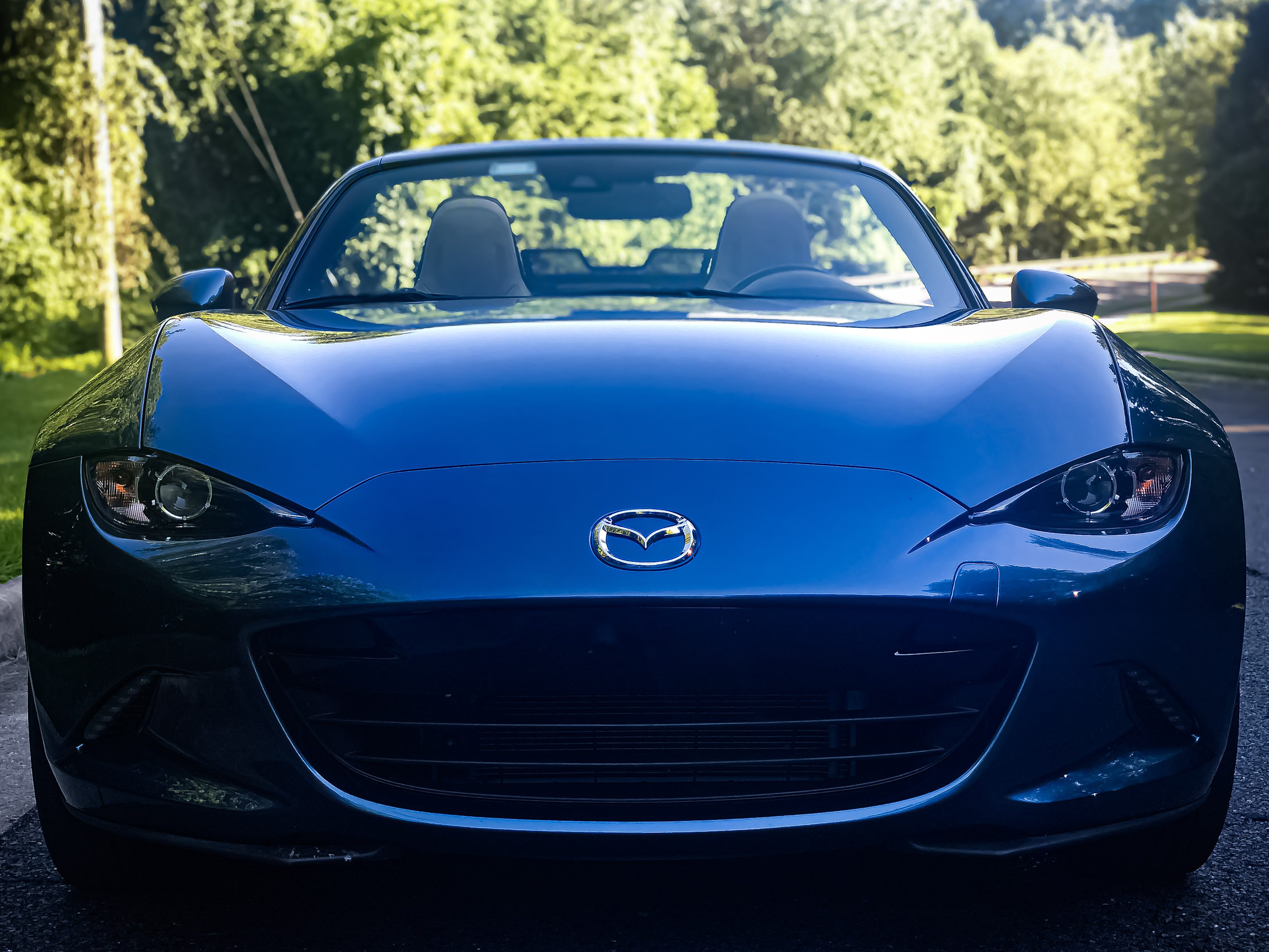 Blue Mazda convertible sports car parked outdoors on a sunny day.