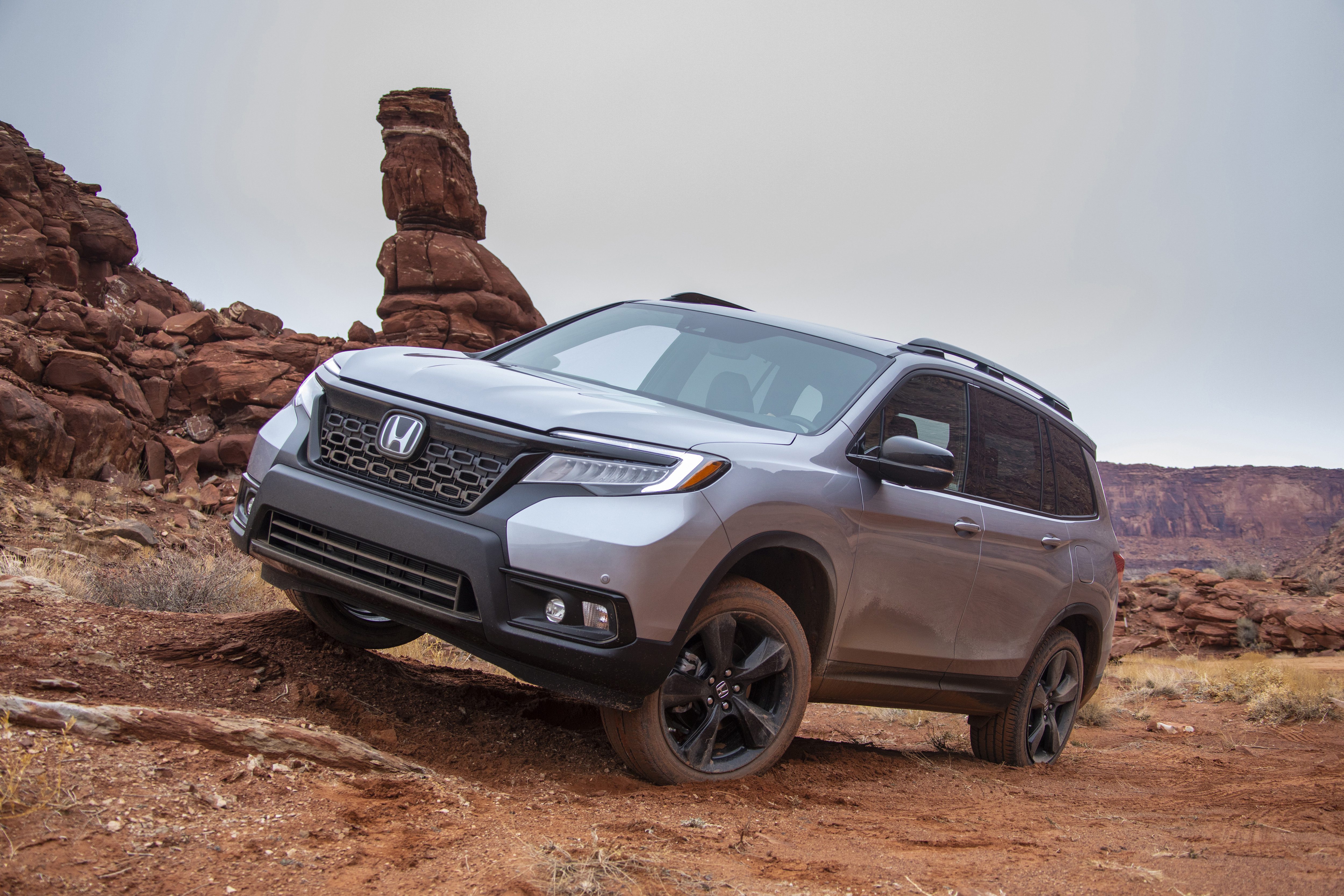 A silver SUV parked on rocky terrain under an overcast sky.