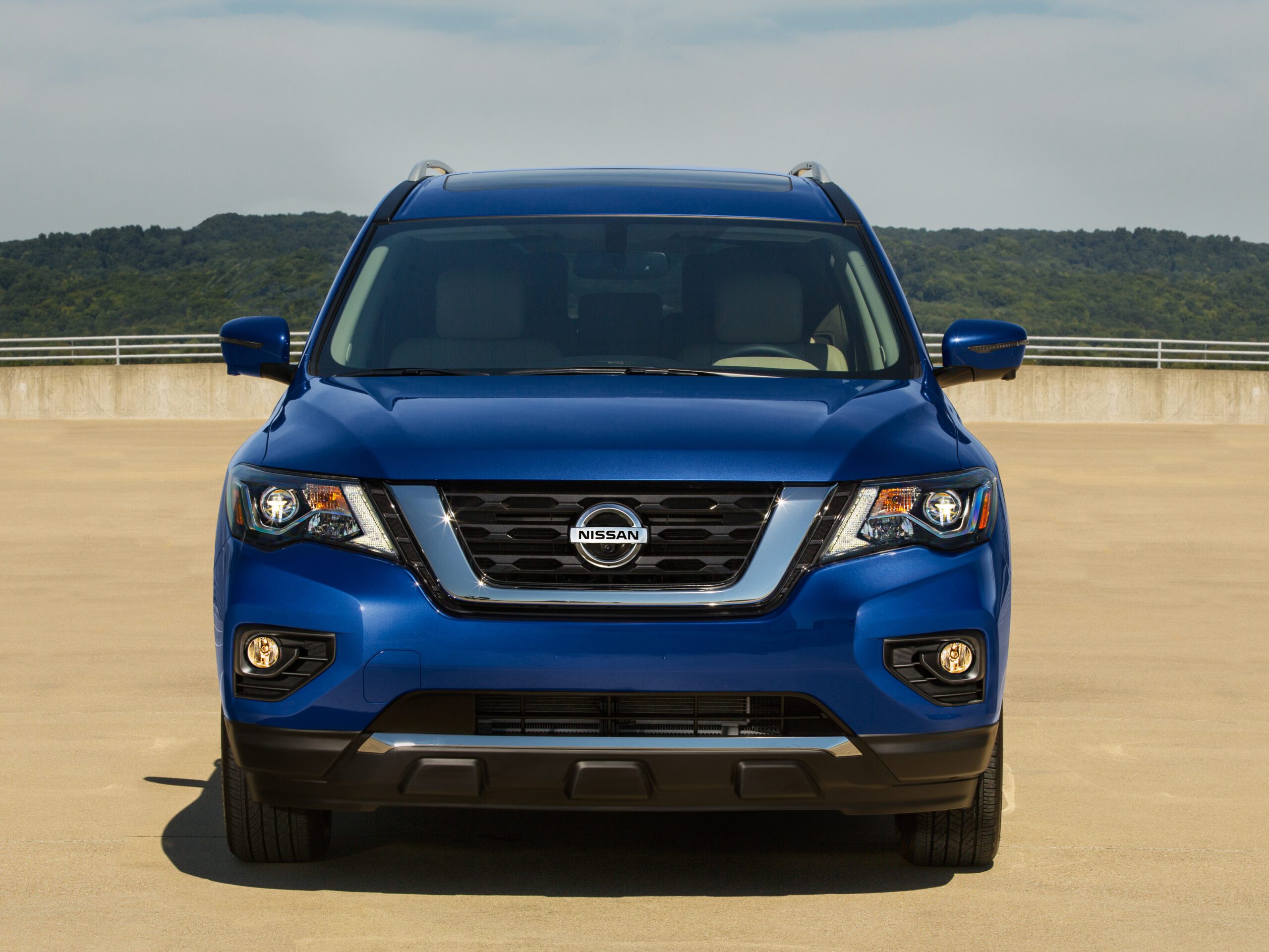 Front view of a blue Nissan SUV on a sandy terrain.
