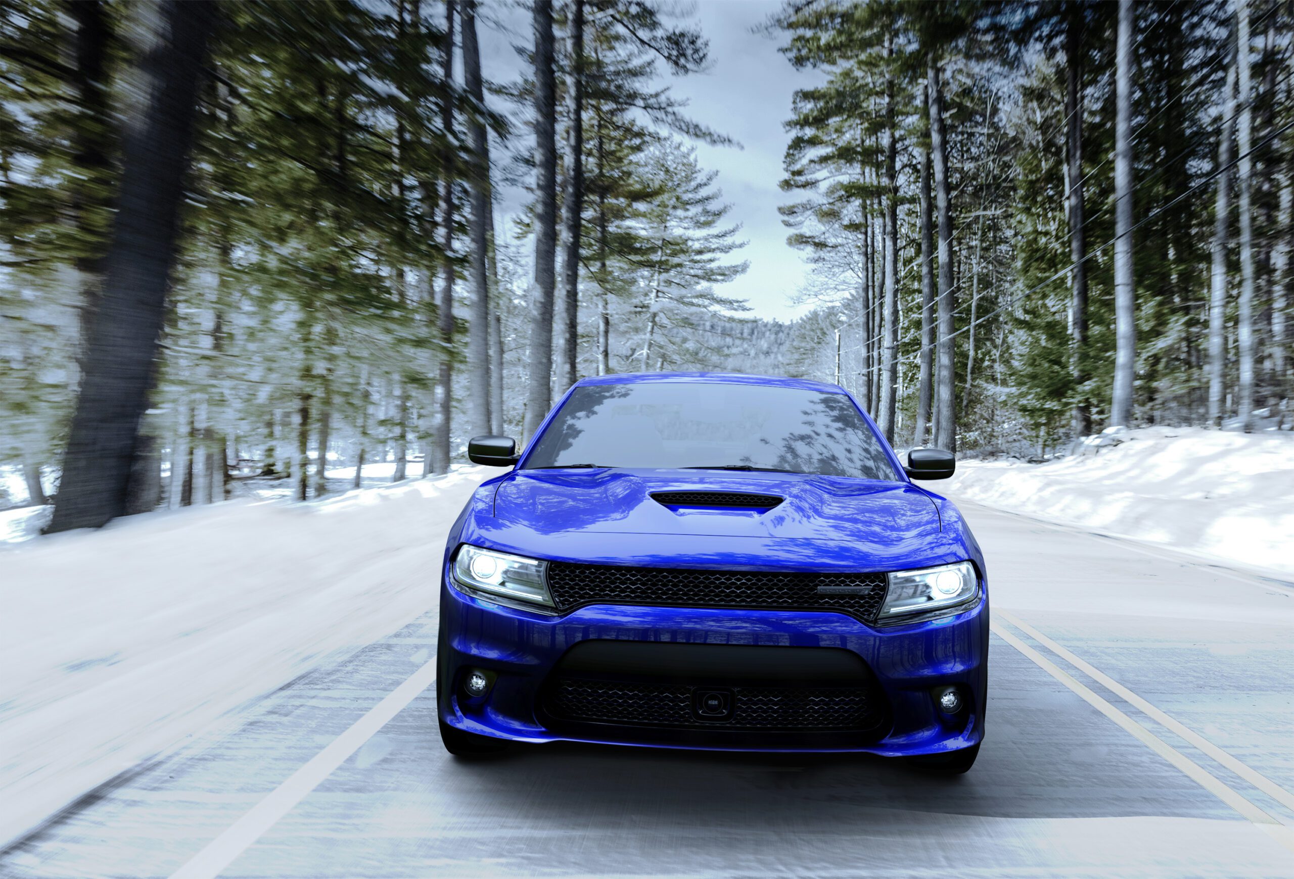 Blue sports car driving on a snowy forest road.