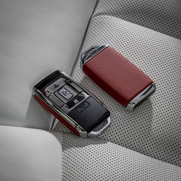 A sleek car key and leather wallet on a gray car seat.