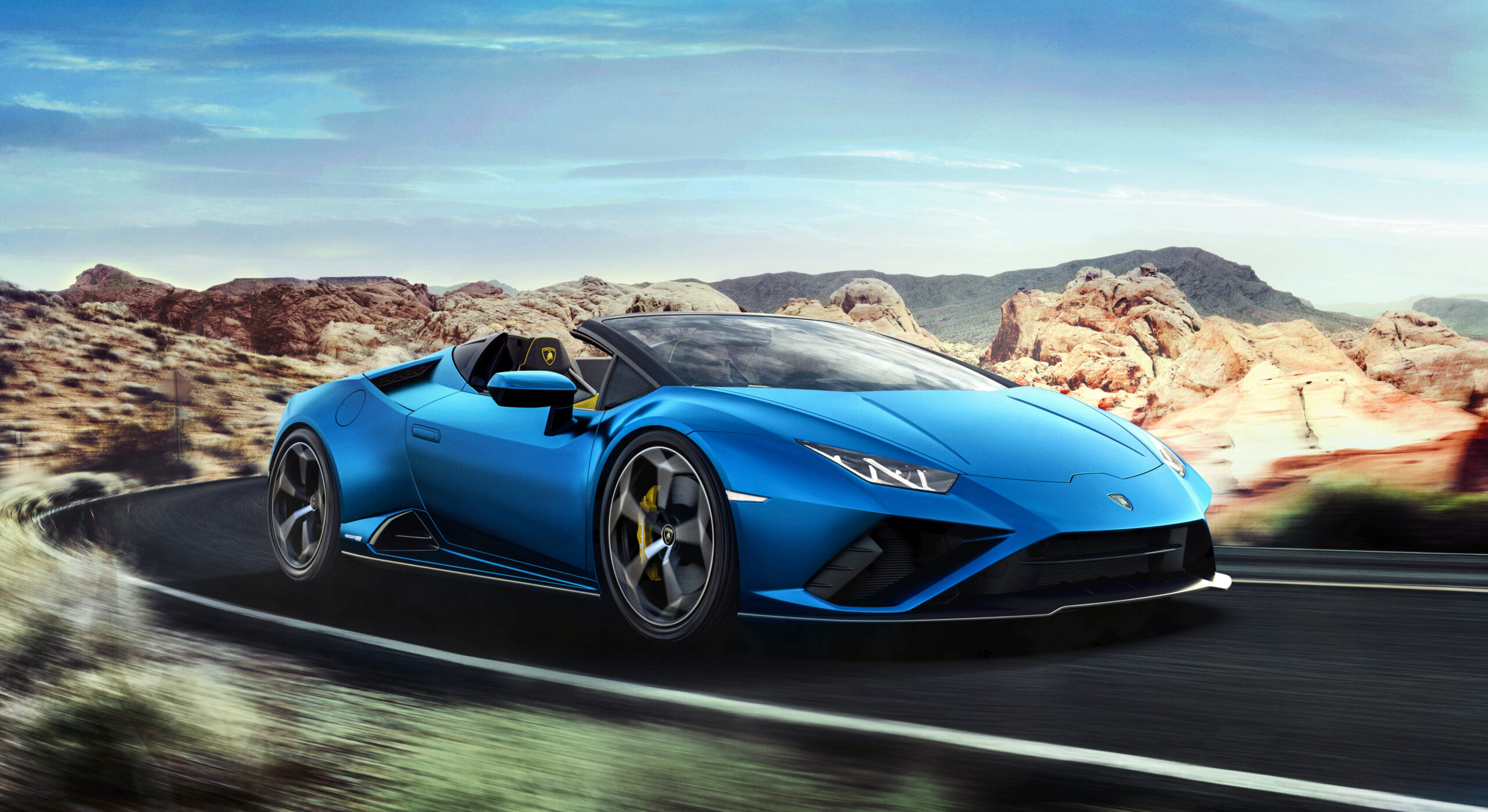 A sleek blue Lamborghini convertible driving on a desert road.
