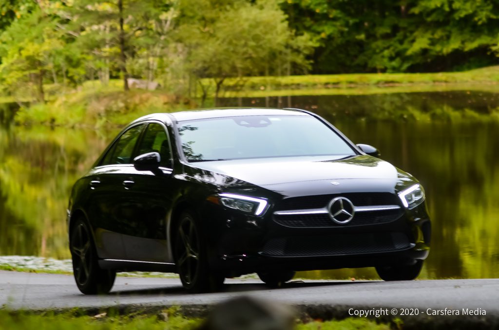 Black Mercedes-Benz parked near a serene lake with greenery.