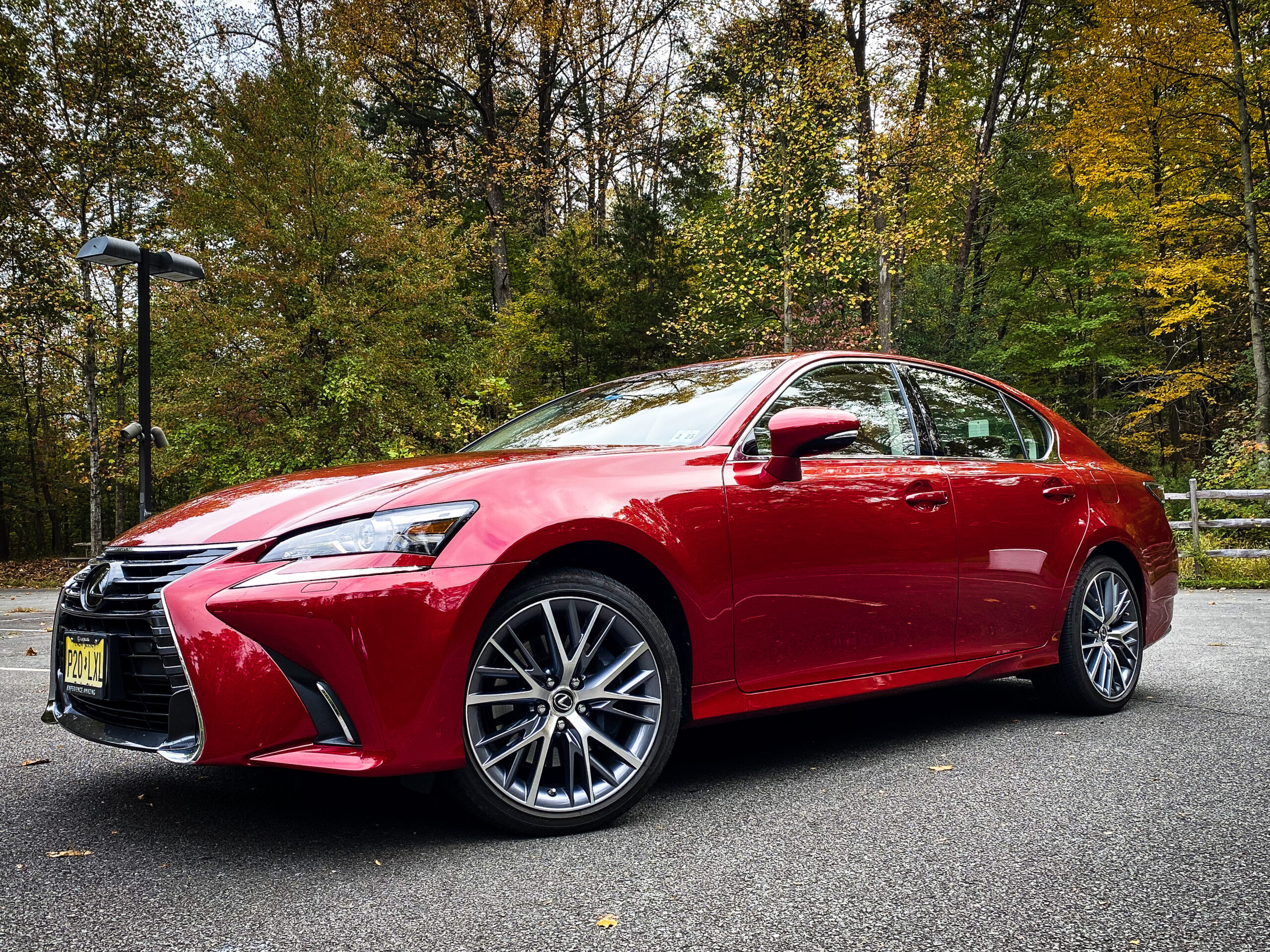 Red luxury sedan parked on a forest road in autumn.