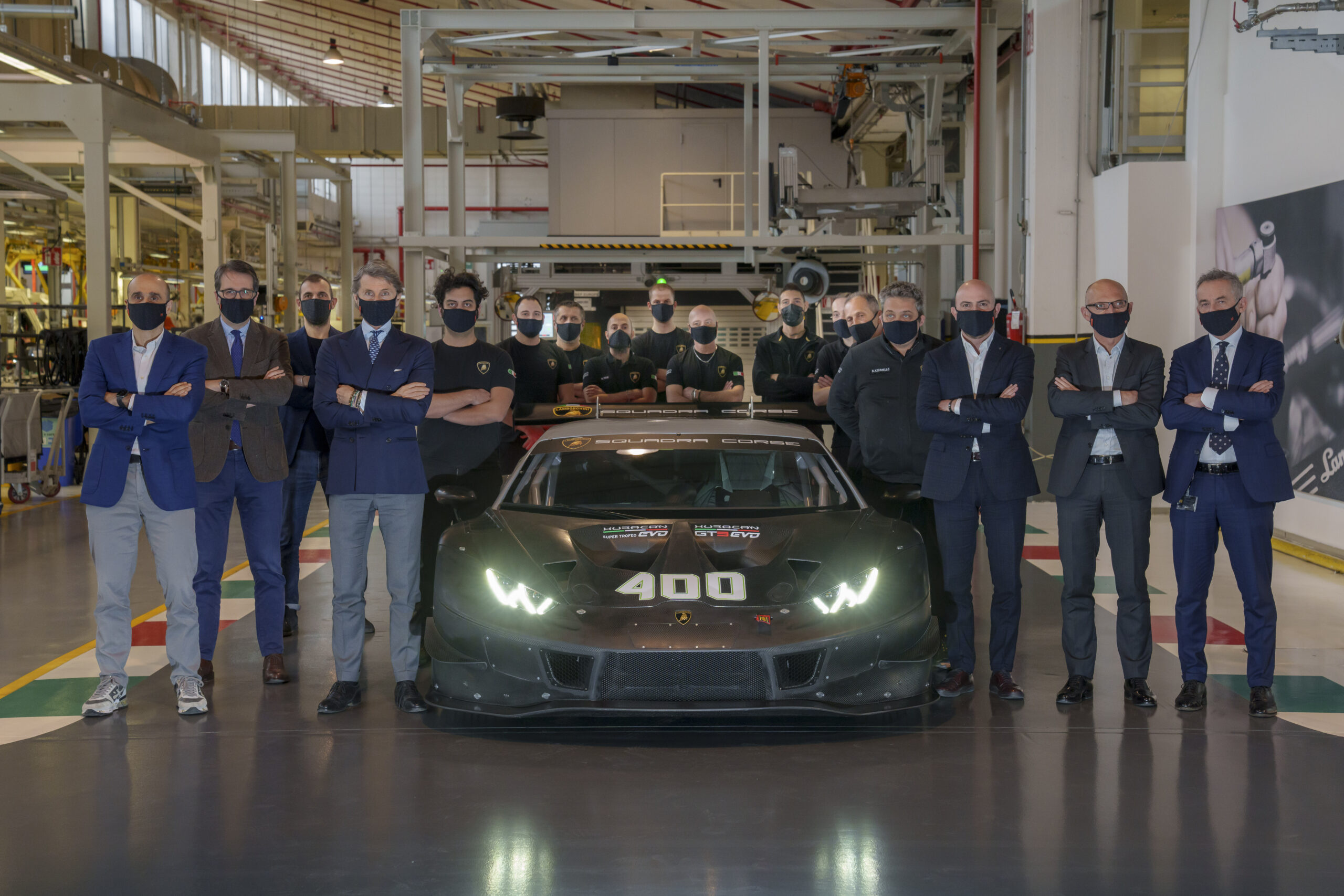 A group of people posing around a sleek race car in a workshop.
