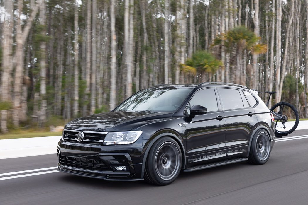 Sleek black Volkswagen SUV driving on a forest road.