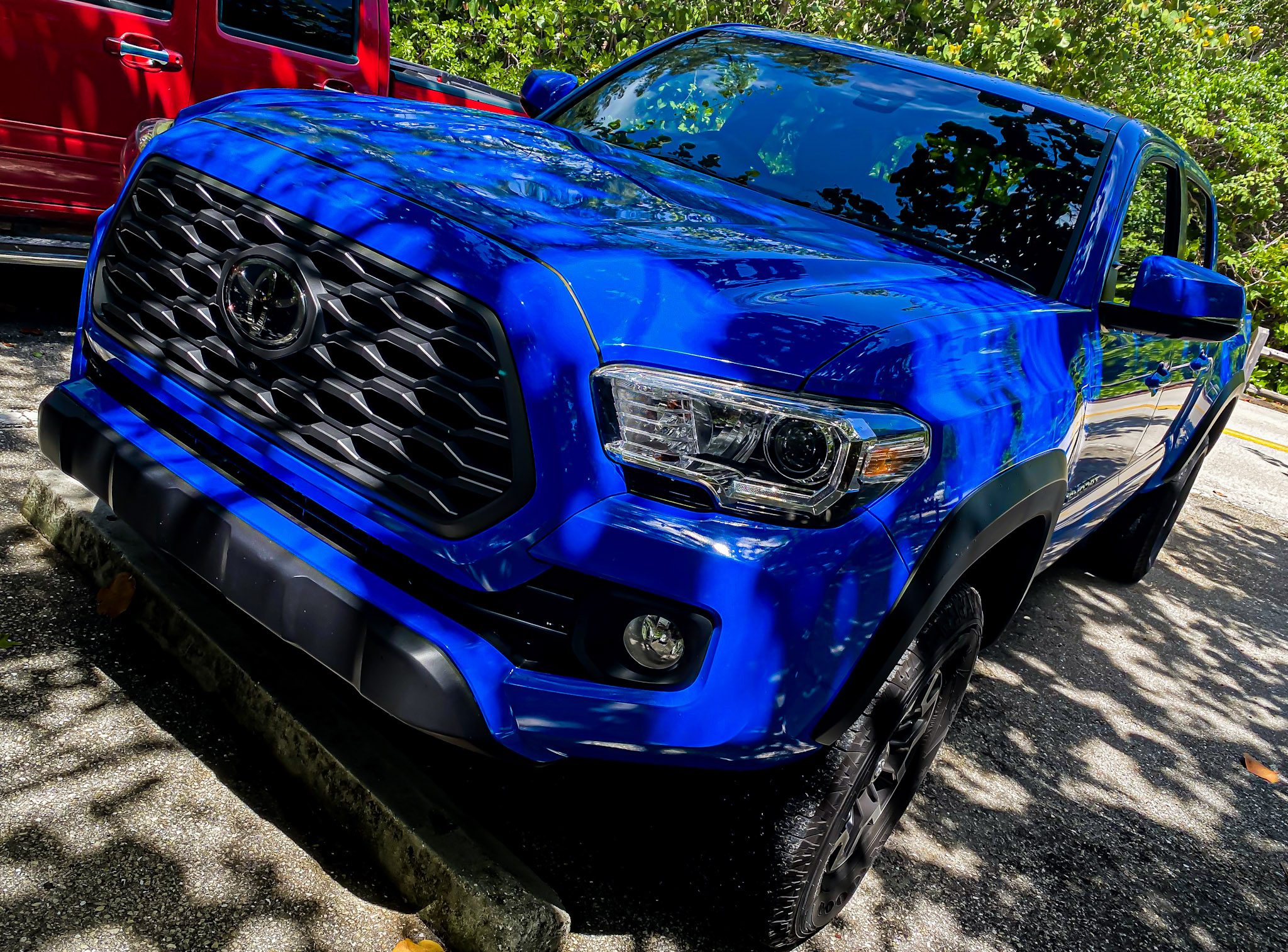 Blue pickup truck parked under dappled sunlight and shadows.