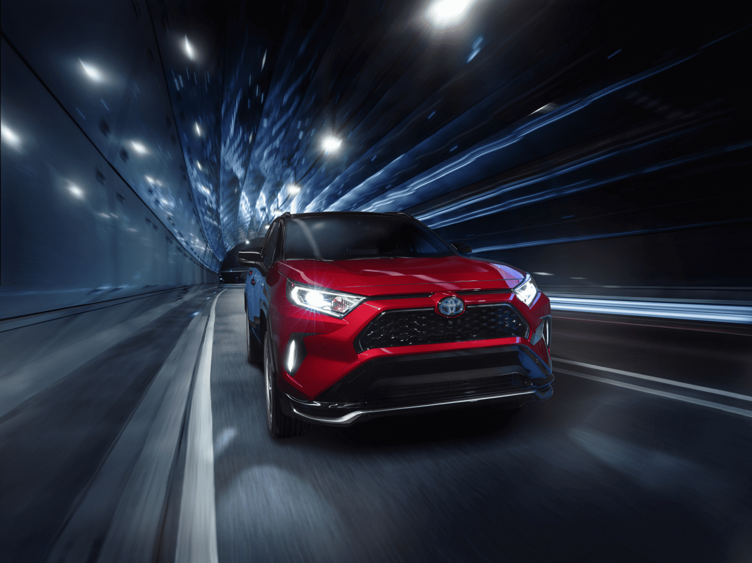Red SUV driving fast through a tunnel at night.