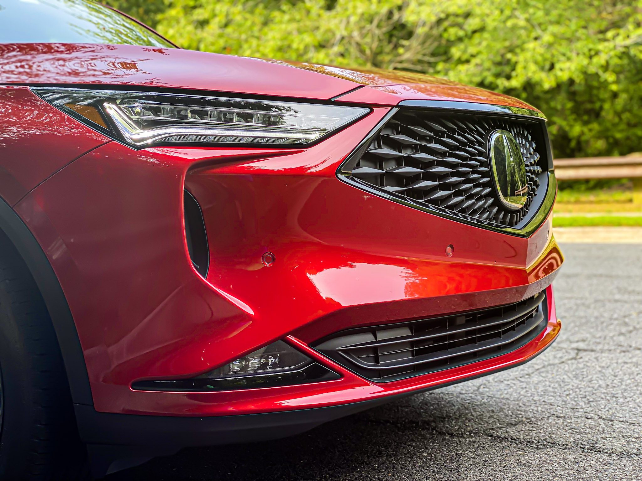 Close-up of a red car's front grille and headlight.