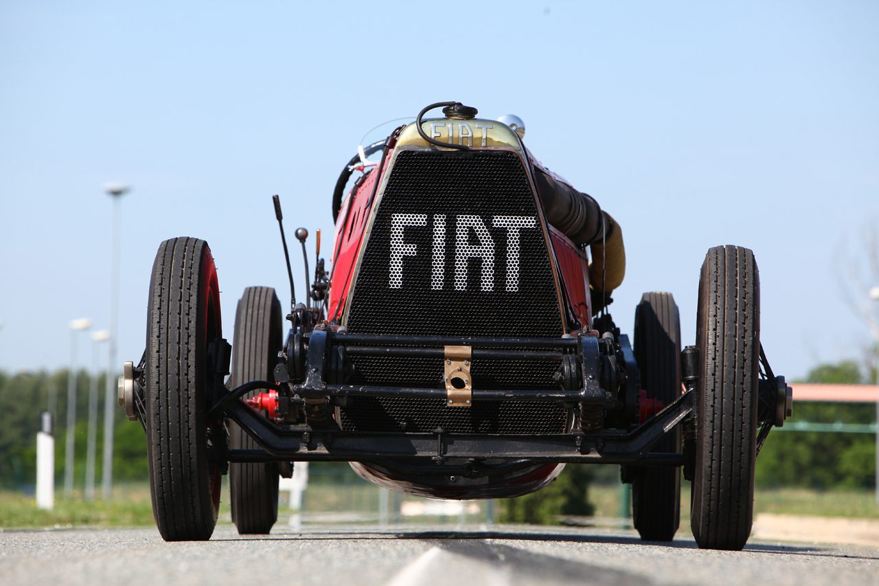 Rear view of a vintage Fiat race car on a track.