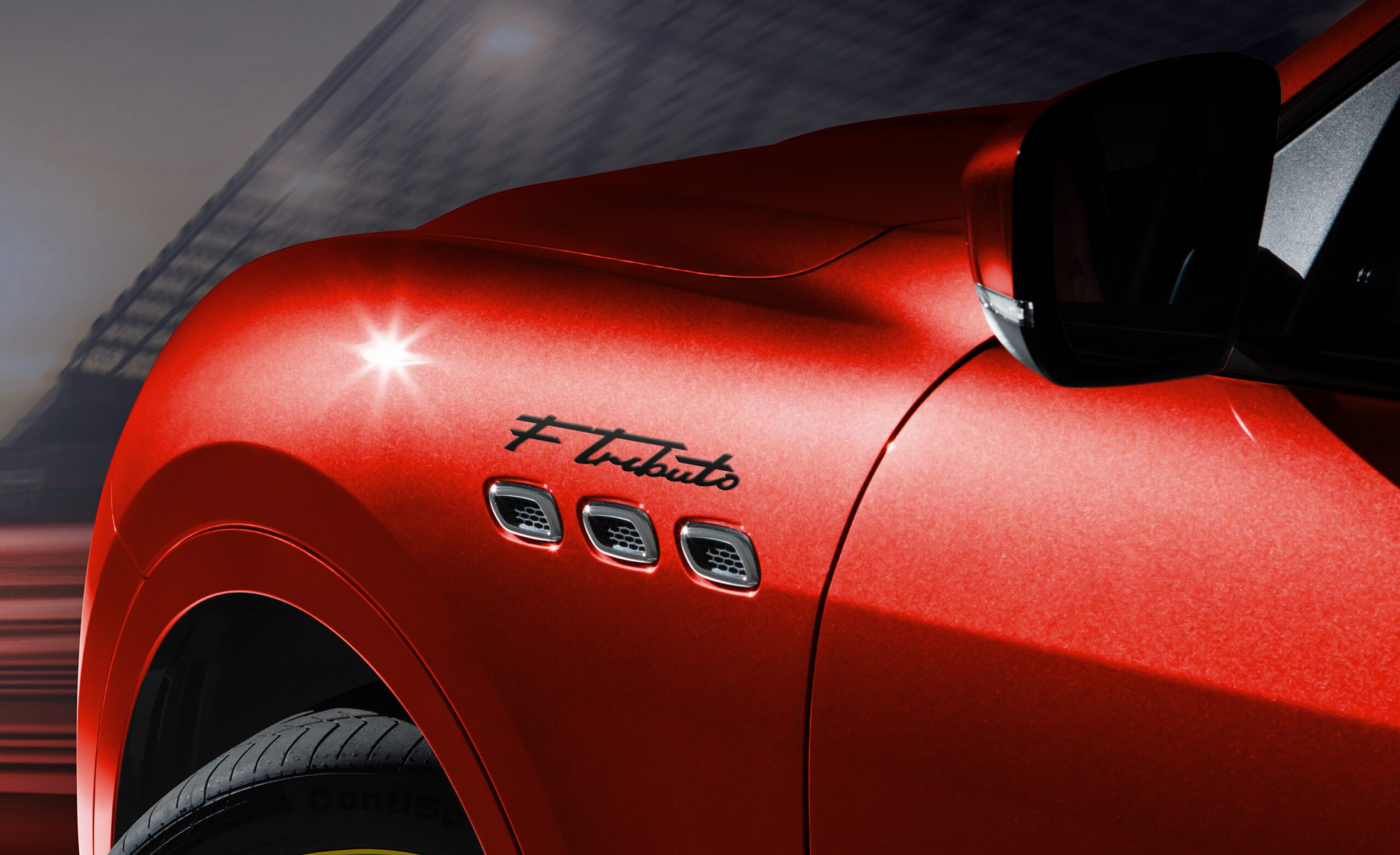 Close-up of a red Maserati car showing the iconic triple side vents and logo.