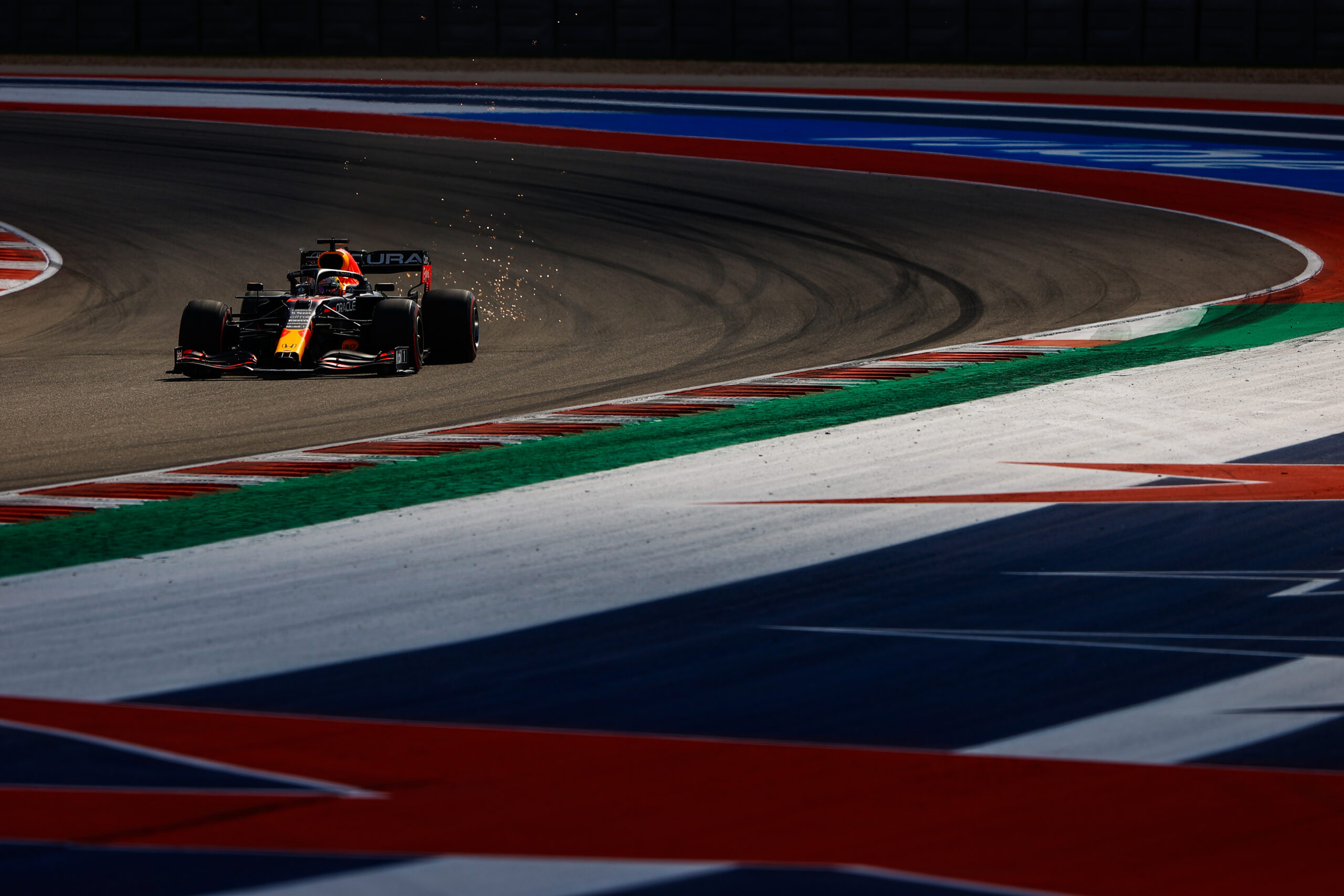 A race car speeds on a colorful Formula 1 track at sunset.