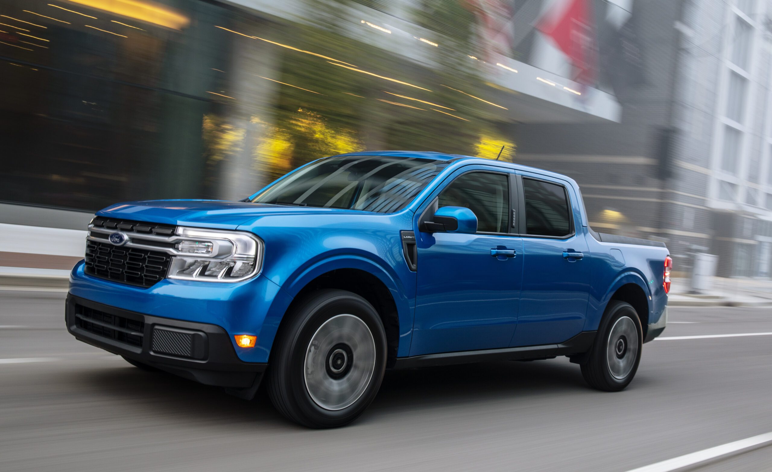 Blue pickup truck driving on a city street in motion.