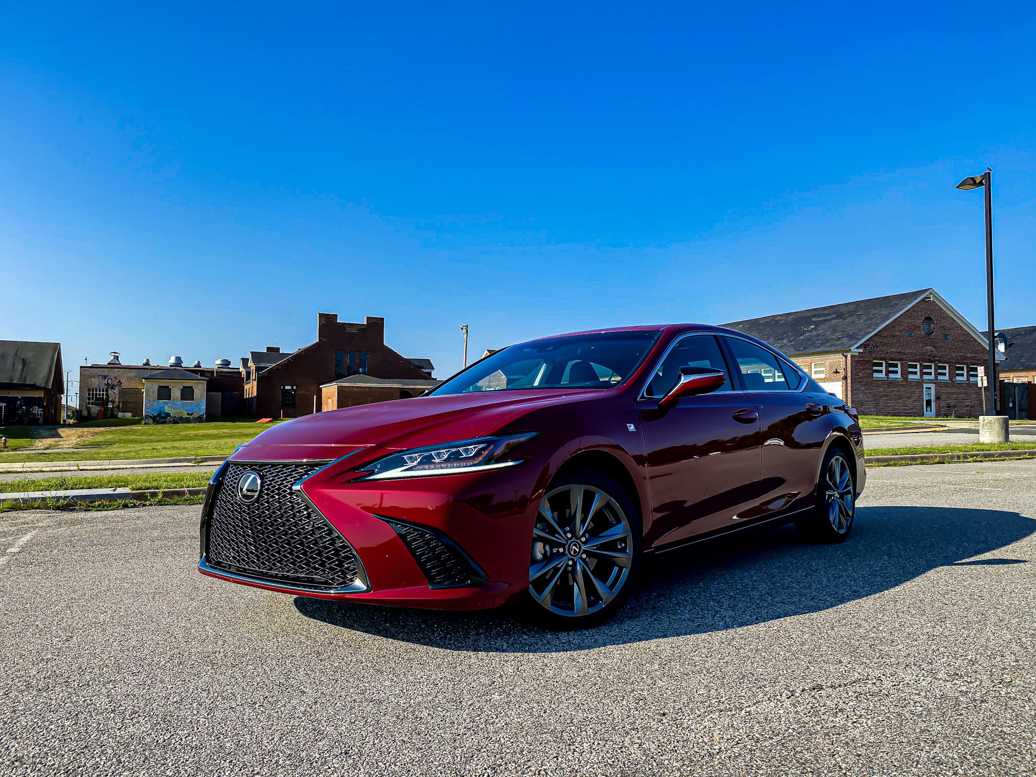 A sleek red luxury sedan parked on a sunny residential street.